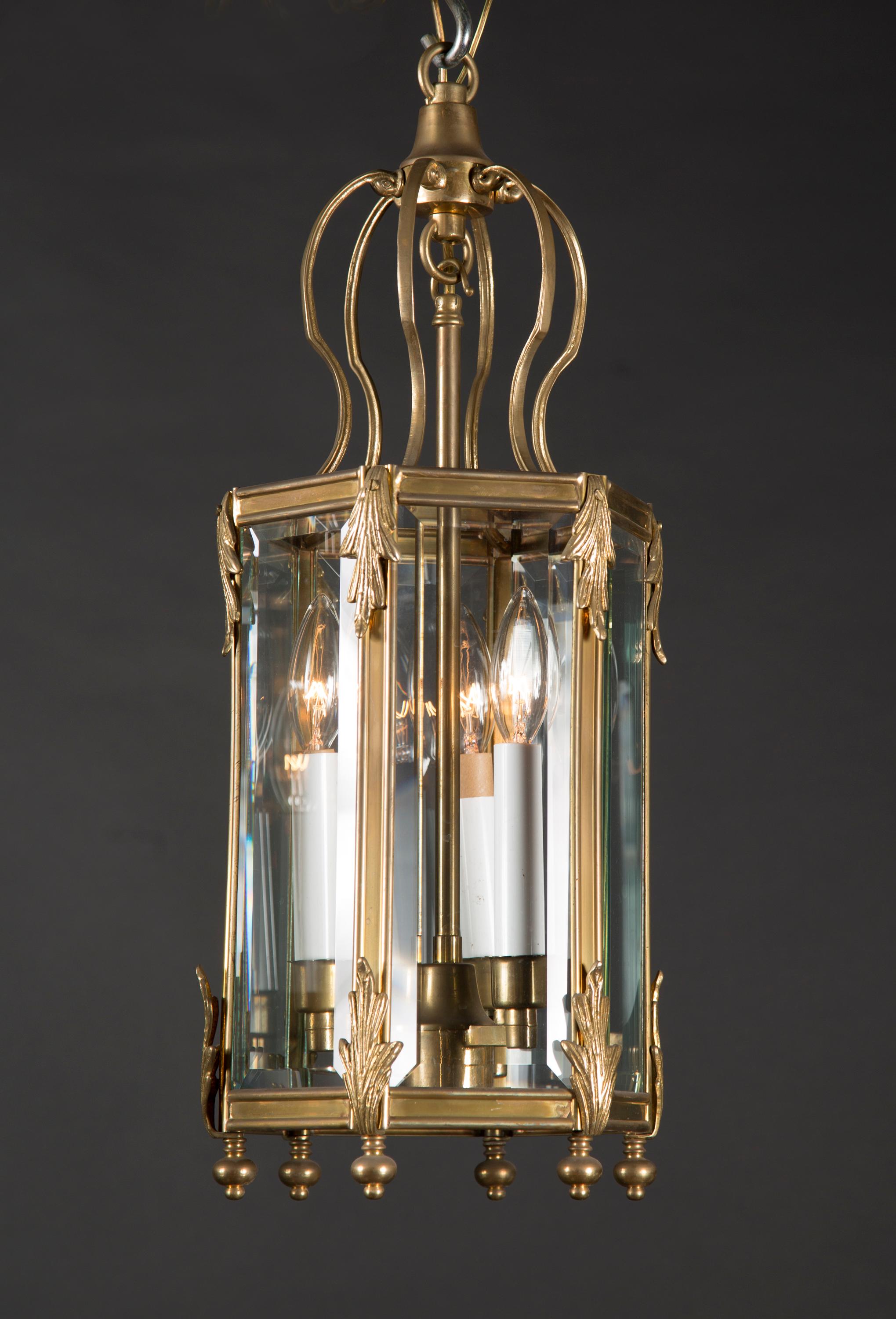This pair of French hexagonal lanterns dates back to the mid 20th century. Made of bronze, they feature six panels of bevelled glass. The bird cage shaped top extends down to the hexagonal center which features twelve detailed acanthus leaves and