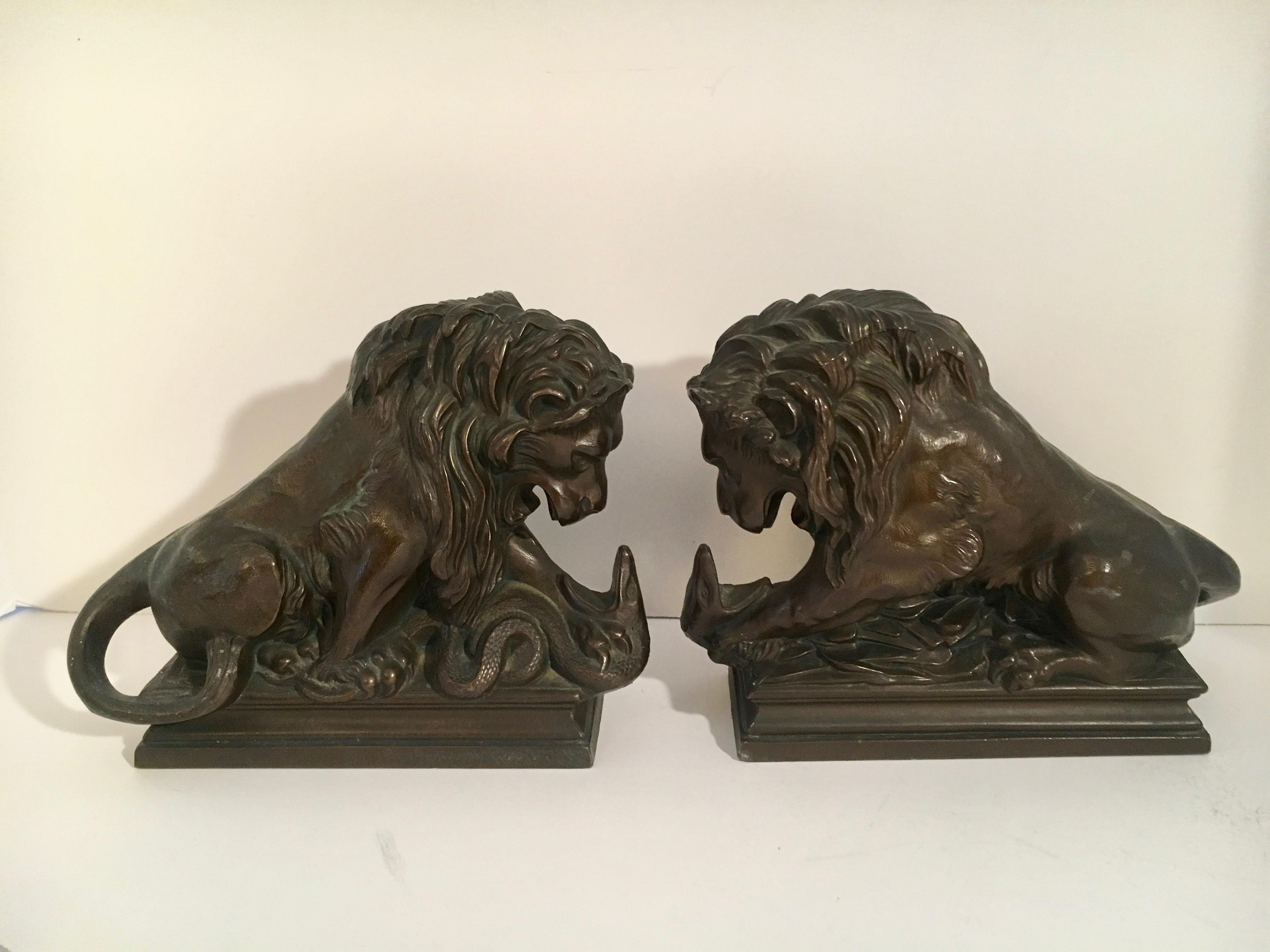 Pair of bronze over metal lions wrestling with serpent - a handsome pair suitable for any office or shelf. A beautifully graceful stance.