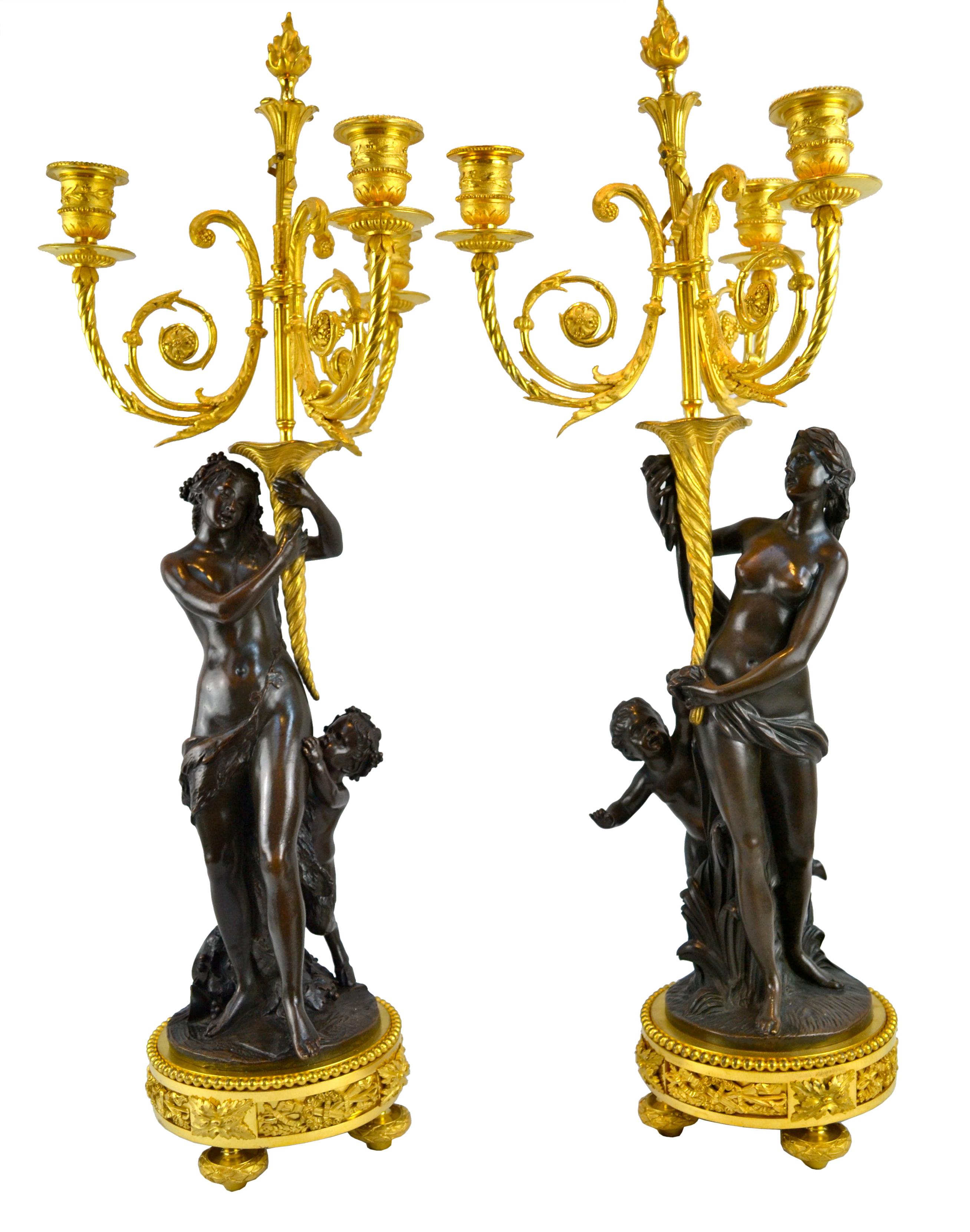 A pair of Clodion inspired figural candelabra of the highest quality gilt and patinated chased bronze. Each show a standing classically draped semi-nude maiden with a hoof footed infant satyr standing behind and pulling on the maidens' robes for