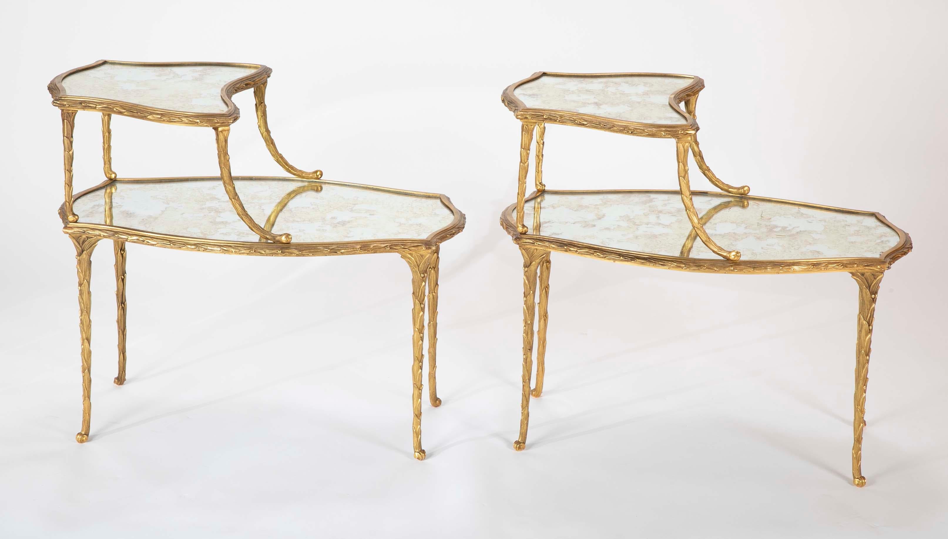 A fabulous pair of finely chased two tier bronze Maison Charles side tables having mirror tops.