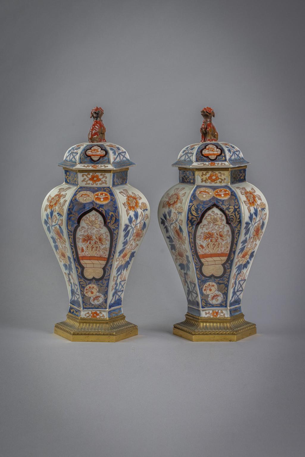 Imari-Stil mit Tafeln mit Blattwerk auf weißem Grund im Wechsel mit Tafeln auf blauem Unterglasurgrund mit Röschen und Blumen in einer Vase. Die Abdeckungen sind ähnlich verziert und mit einem Fohlenhund versehen.