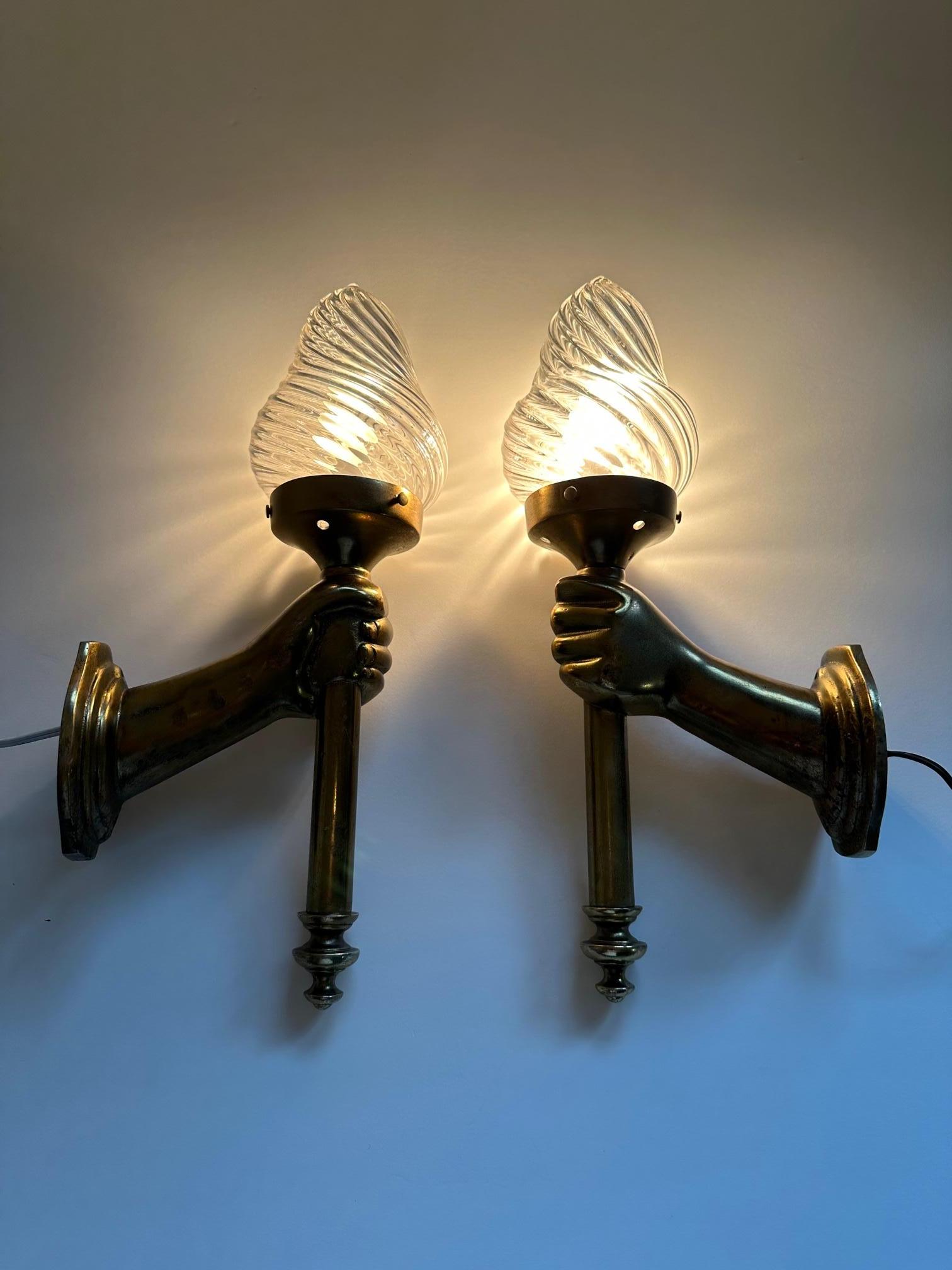 Very dramatic pair of sconces having bronze patinated cast metal hands that extend from the wall and hold torches with lovely blown glass shades.