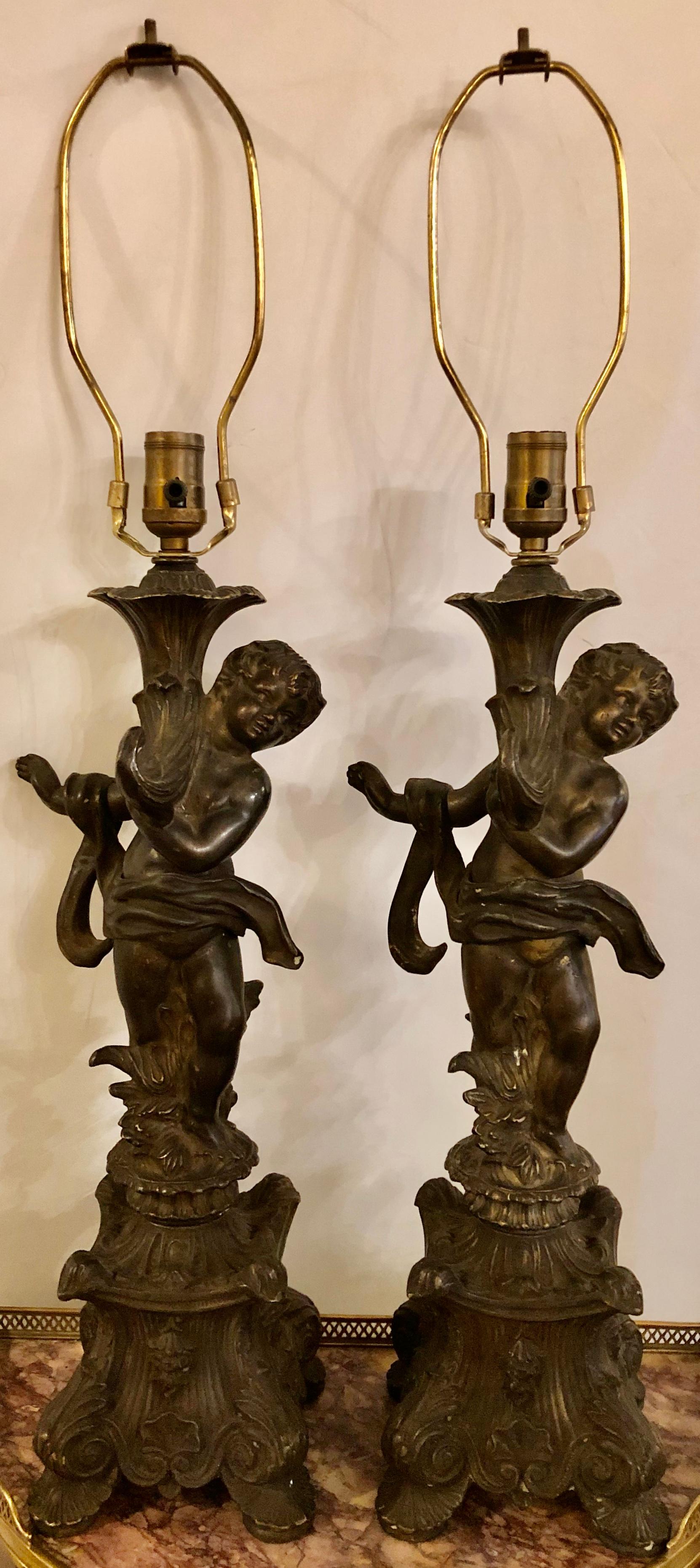 Pair of bronze patinated putti table lamps each in the Louis XVI manner holding up a cornucopia on top of a pedestal base. Each lamp takes one sixty-watt light bulb.
ISX.