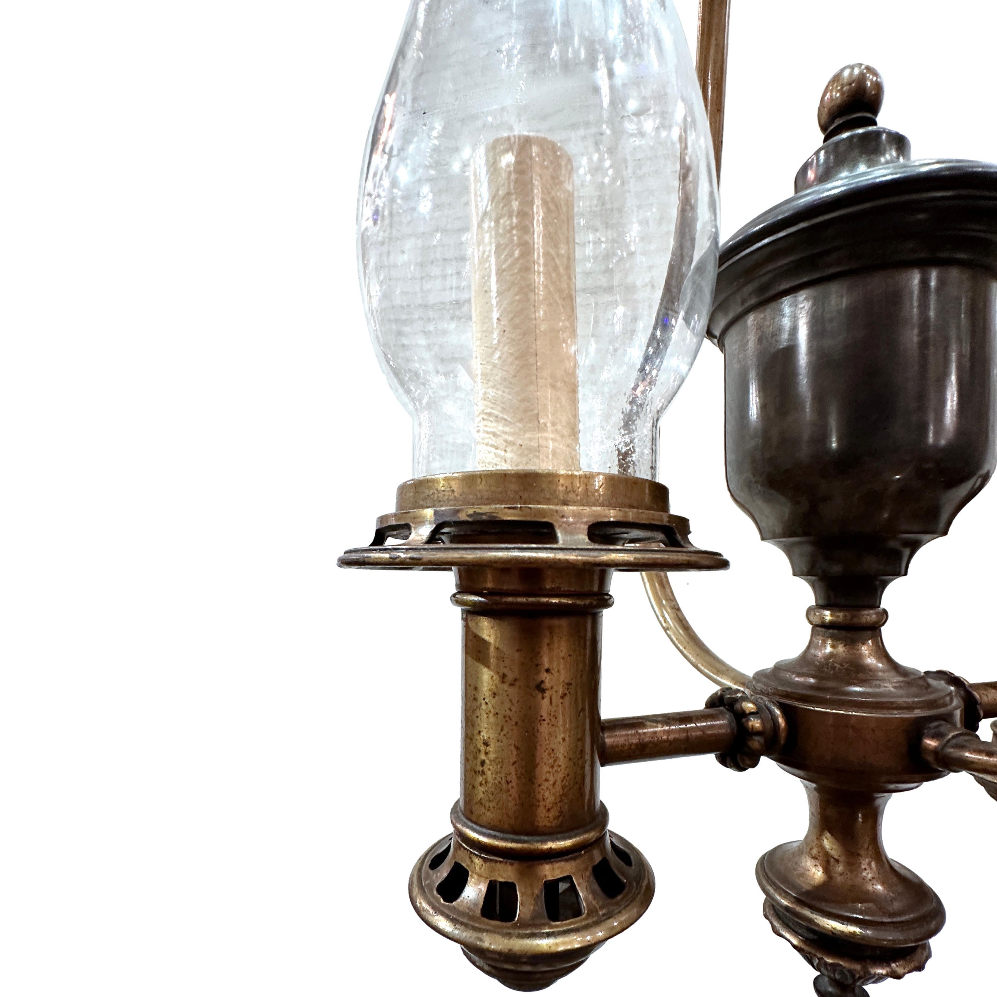 Pair of American circa 1930's bronze and pewter double light nautical pendant light fixtures with clear glass hurricanes. Sold individually.

Measurements:
Minimum drop: 20