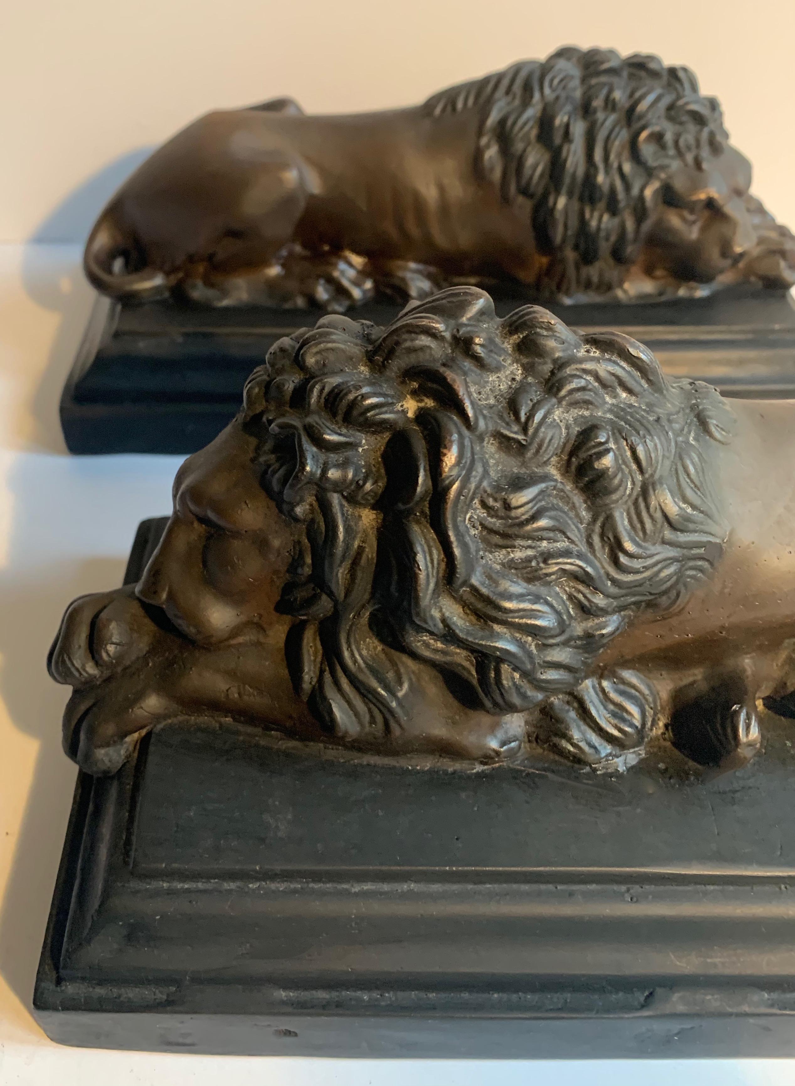 Pair of reclining bronze lions on wood base - a handsome pair ready for the office or den. Bronze sculpture lions reclining on a wood base.