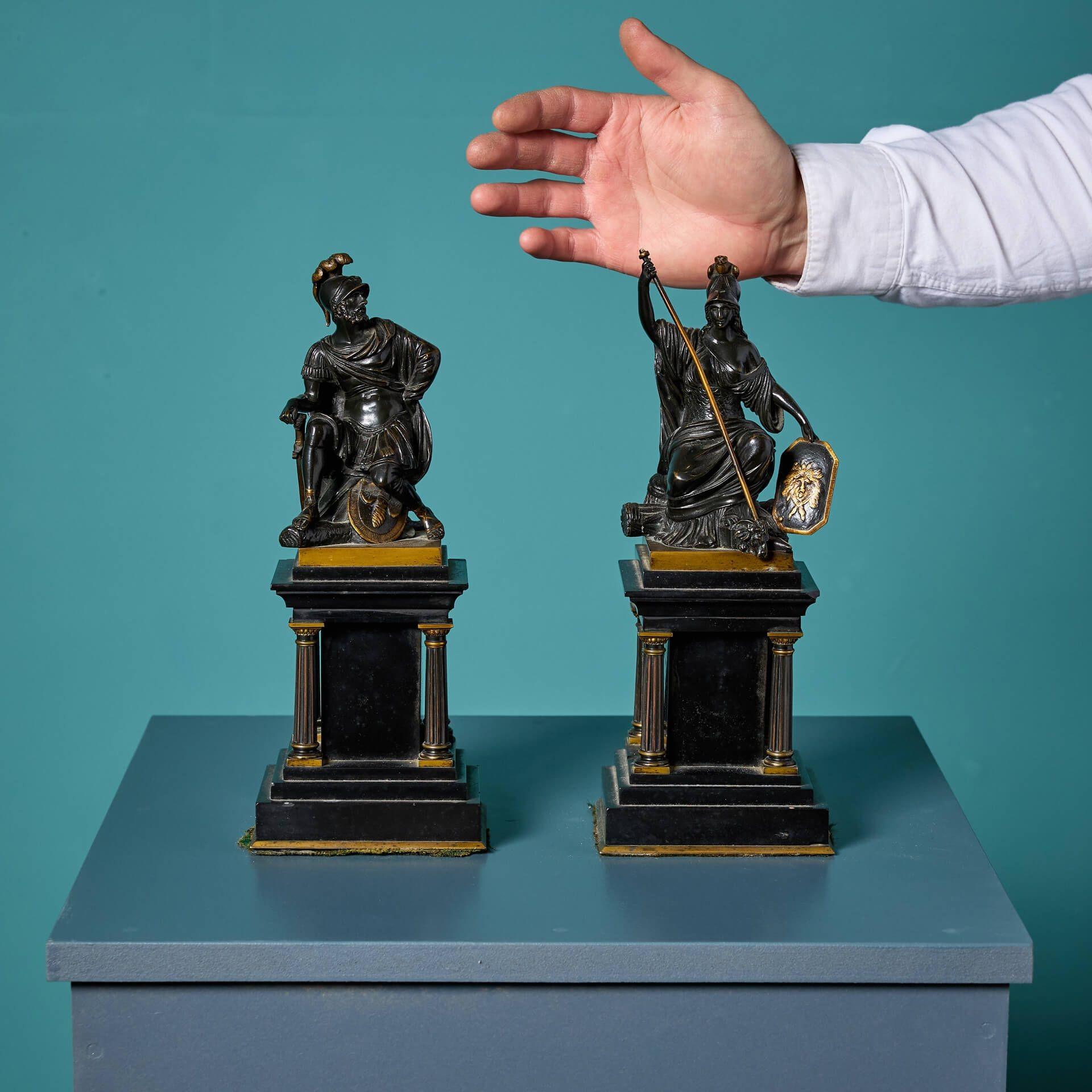 A dramatic pair of antique regency era bronze figures, depicting the Roman God Mars and Goddess Minerva, elevated by stepped black marble bases with neoclassical style columns to the four corners and gilded highlights throughout.

Originating from