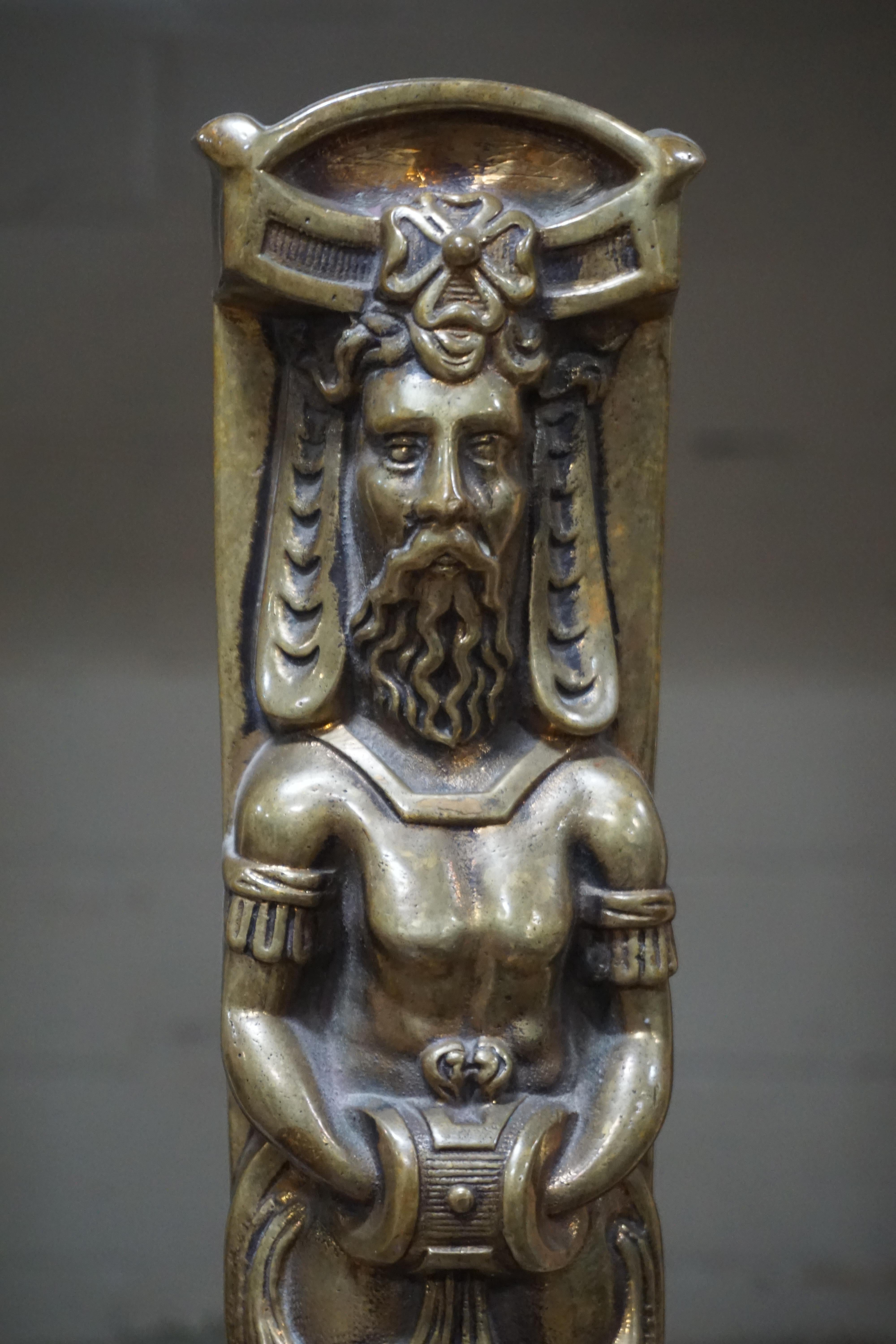 Each in the form of a tapering standard with an elaborate male figurehead, the body of which forms a caduceus, centred with a grape leaf, and terminating in a lion’s paw. The uprights are mounted on elaborate arched bases with paw feet, featuring
