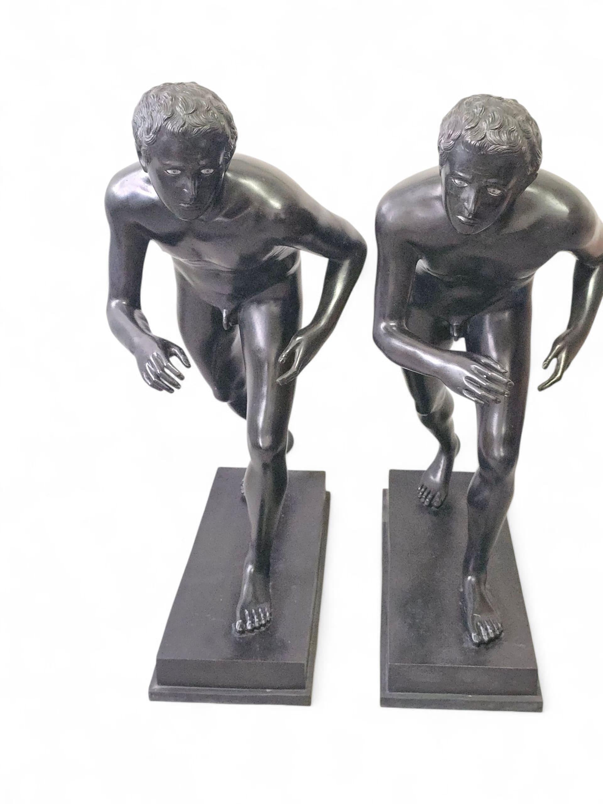 Exceptional reproduction of the renowned pair of bronze runner statues discovered at the Villa of the Papyri in Herculaneum, now housed in the National Archaeological Museum of Naples. These figures are Roman copies from the 1st century BC of lost