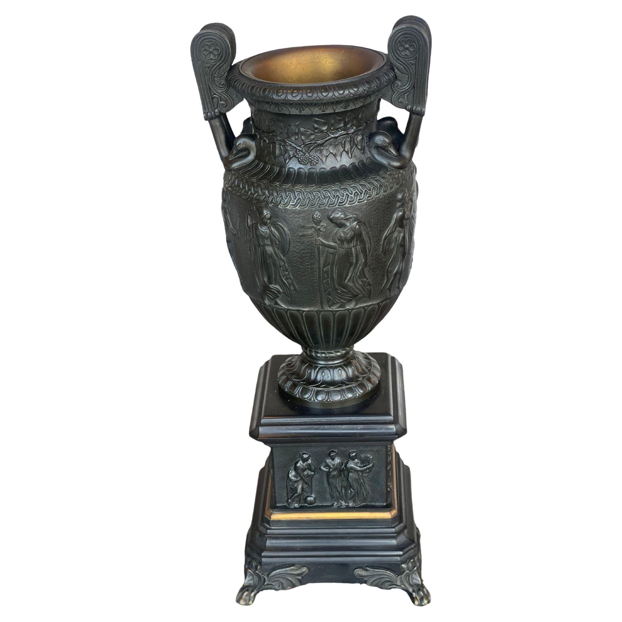 Coppia di urne in bronzo e ardesia in stile neoclassico della fine del XIX secolo. Rilievo decorato con figure classiche greco-romane e fogliame, affiancato da manici di cigno, con fodere.