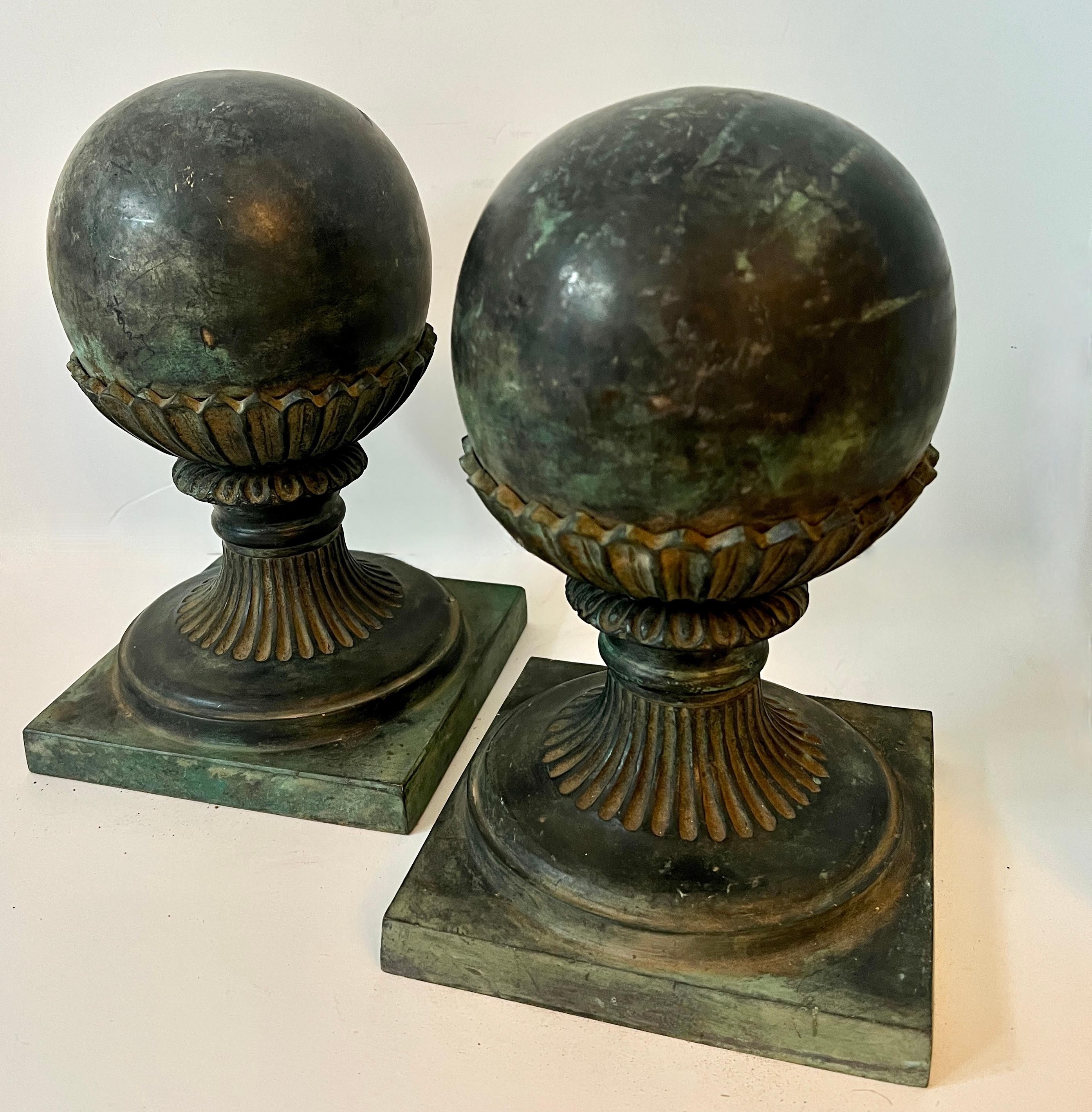 Pair of patinated spherical bronze finials on a fluted pedestal base.

The pair work well on a console or hall table as decor, or flanking a fireplace or large table, and also great garden decor.  At 11 inches tall and 8.5 pounds each make terrific