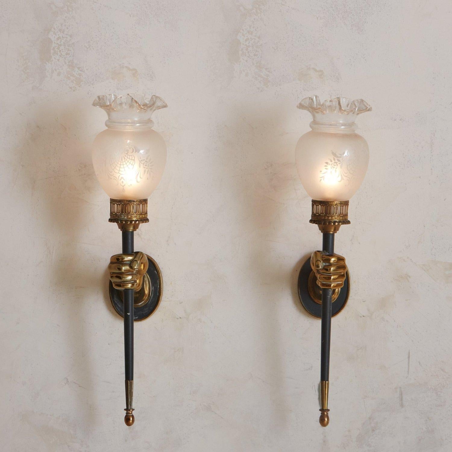 A pair of 1960s sconces by Parisian firm, Maison Arlus. This pair features bronze hand motifs which hold elegantly angled black lacquered torch arms. They have circular wall plates and retain their original frosted glass shades with etched floral