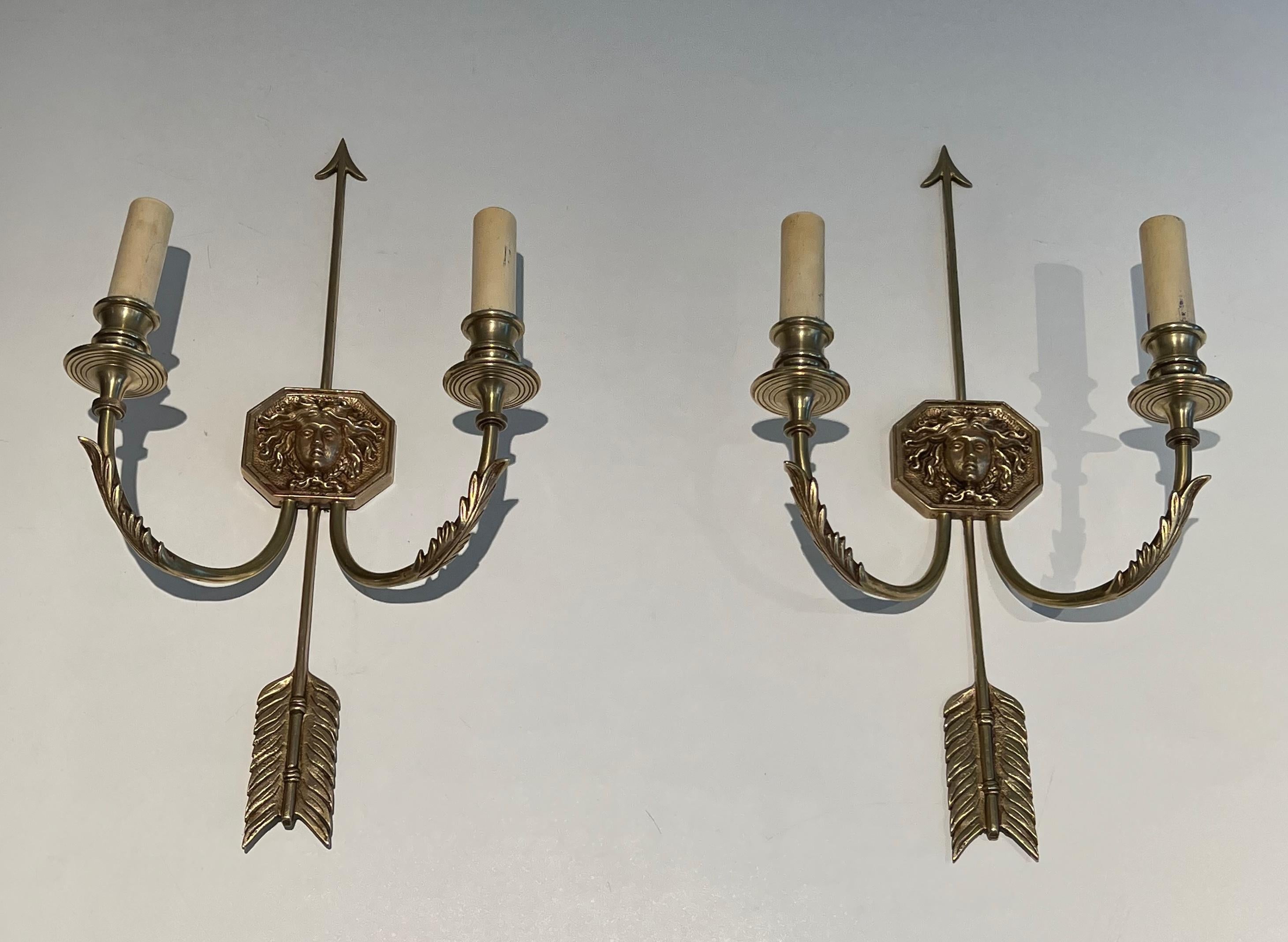 Dieses sehr schöne und elegante Paar Wandleuchter ist aus fein ziselierter Bronze gefertigt und zeigt einen bronzenen Pfeil mit dem Bildnis des Sonnenkönigs. Es handelt sich um ein französisches Werk im Empire-Stil des berühmten französischen