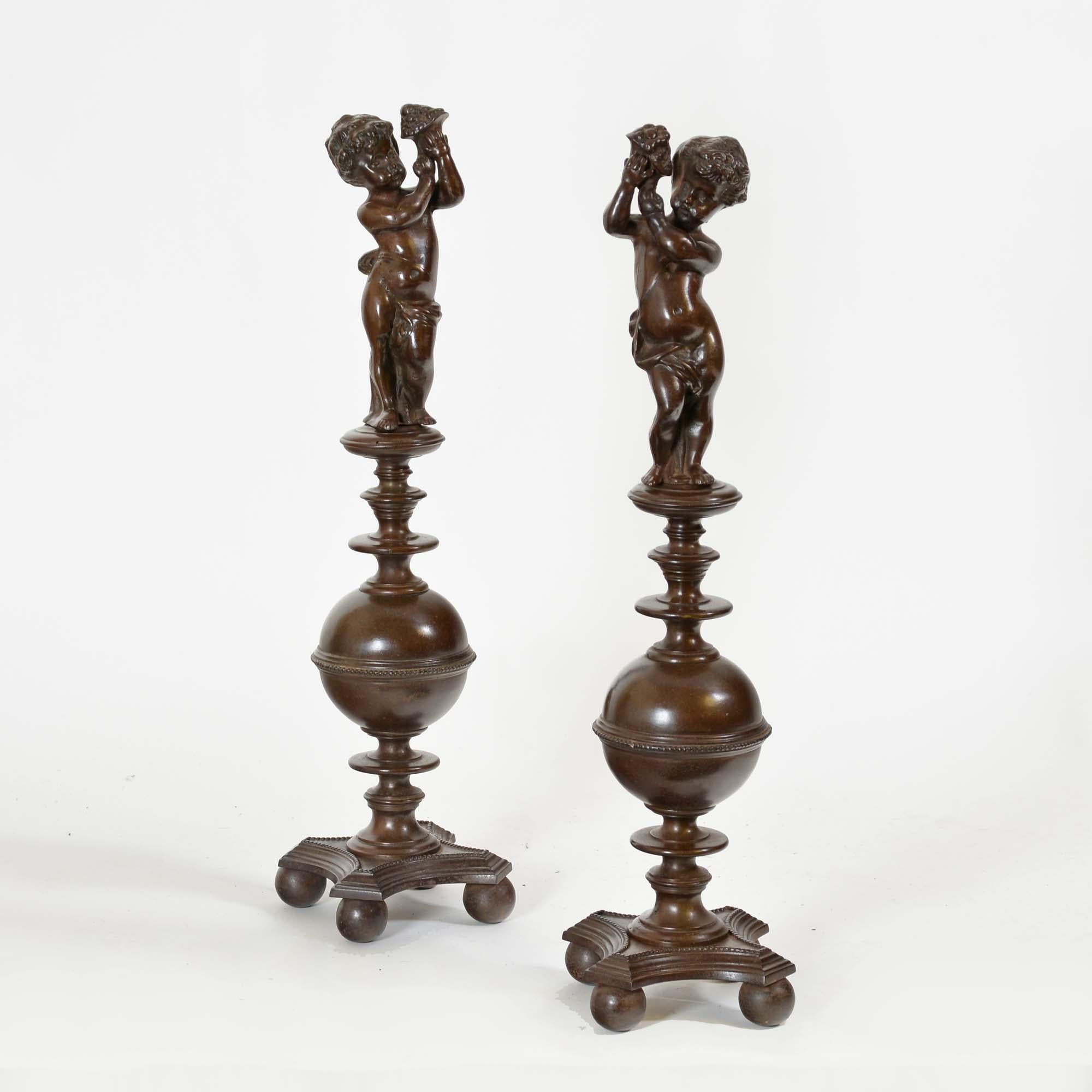 A pair of bronzed cast iron Renaissance style andirons. Each with a figure of a cherub holding a cornucopia, on a ring turned and baluster column over stepped quadripartite plinth bases upon ball feet.  Lovely bronzed patina and condition.
Italian,