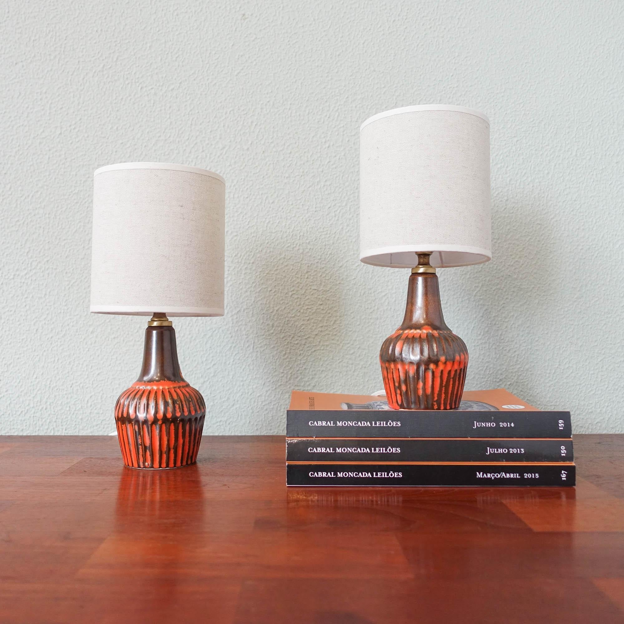 This pair of table lamps were designed and produced by Secla, inn Portugal, during the 1960s. The base is in ceramic with orange and brown tones, resembling the fat-lava technique. The ceramic base is in original and overall in good vintage