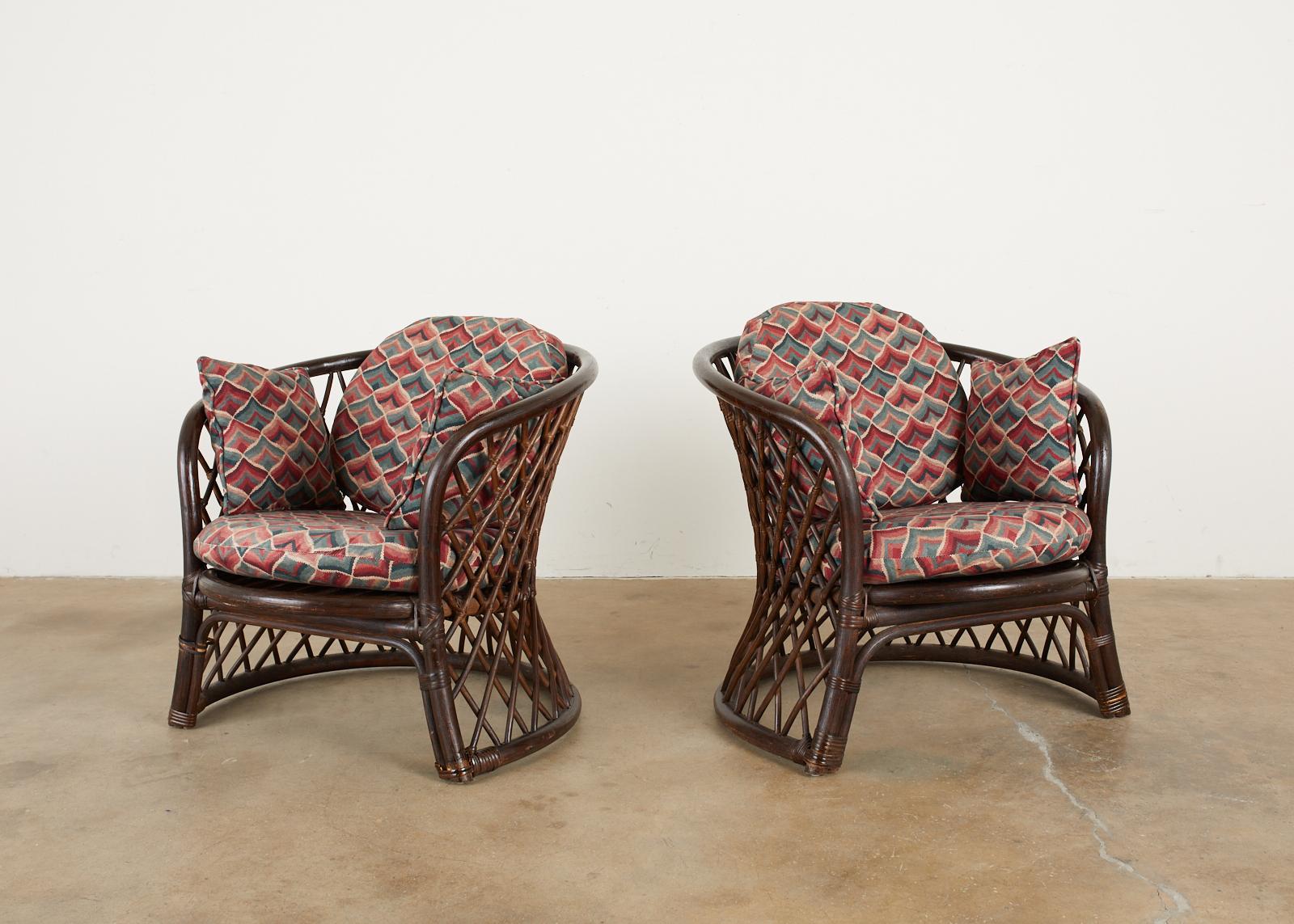Stylish pair of Brown Jordan club chairs or lounge chairs made in the organic modern style from rattan and wicker. The chairs feature a round rattan frame with a waisted form of geometric open fretwork design rattan poles. The rattan is lashed