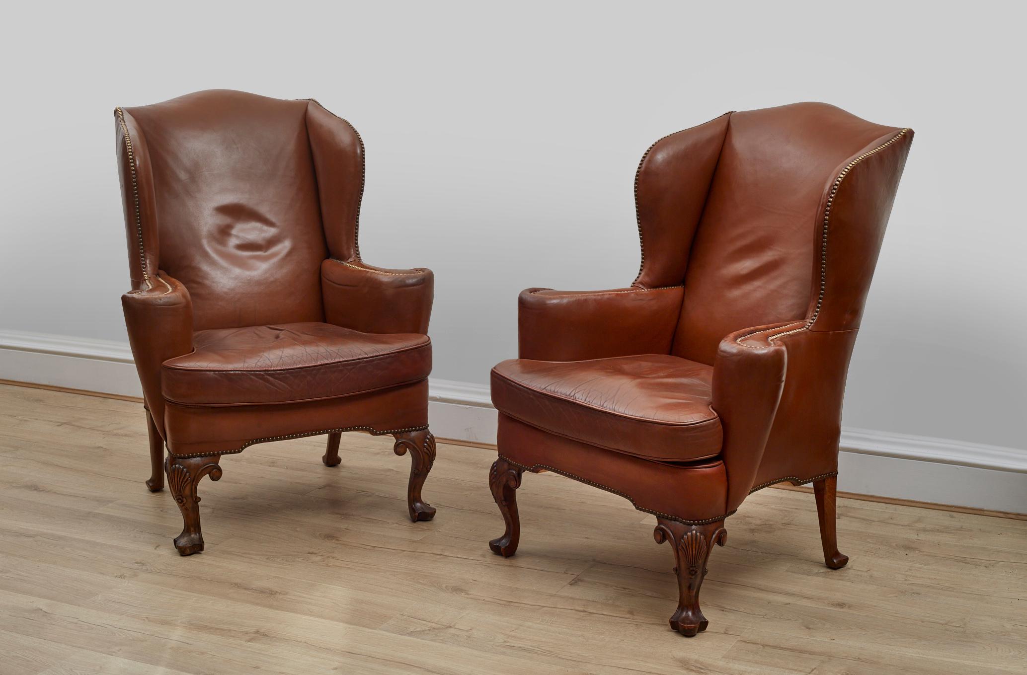 A pair of superb 1920's wingback armchairs in their original brown leather upholstery.  

The feet are curved with ornately carved shell detailing and brass studs. 

Dimensions:
Height: 110 cm 
Width: 83 cm 
Depth: 66 cm
Seat height: 48 cm 



