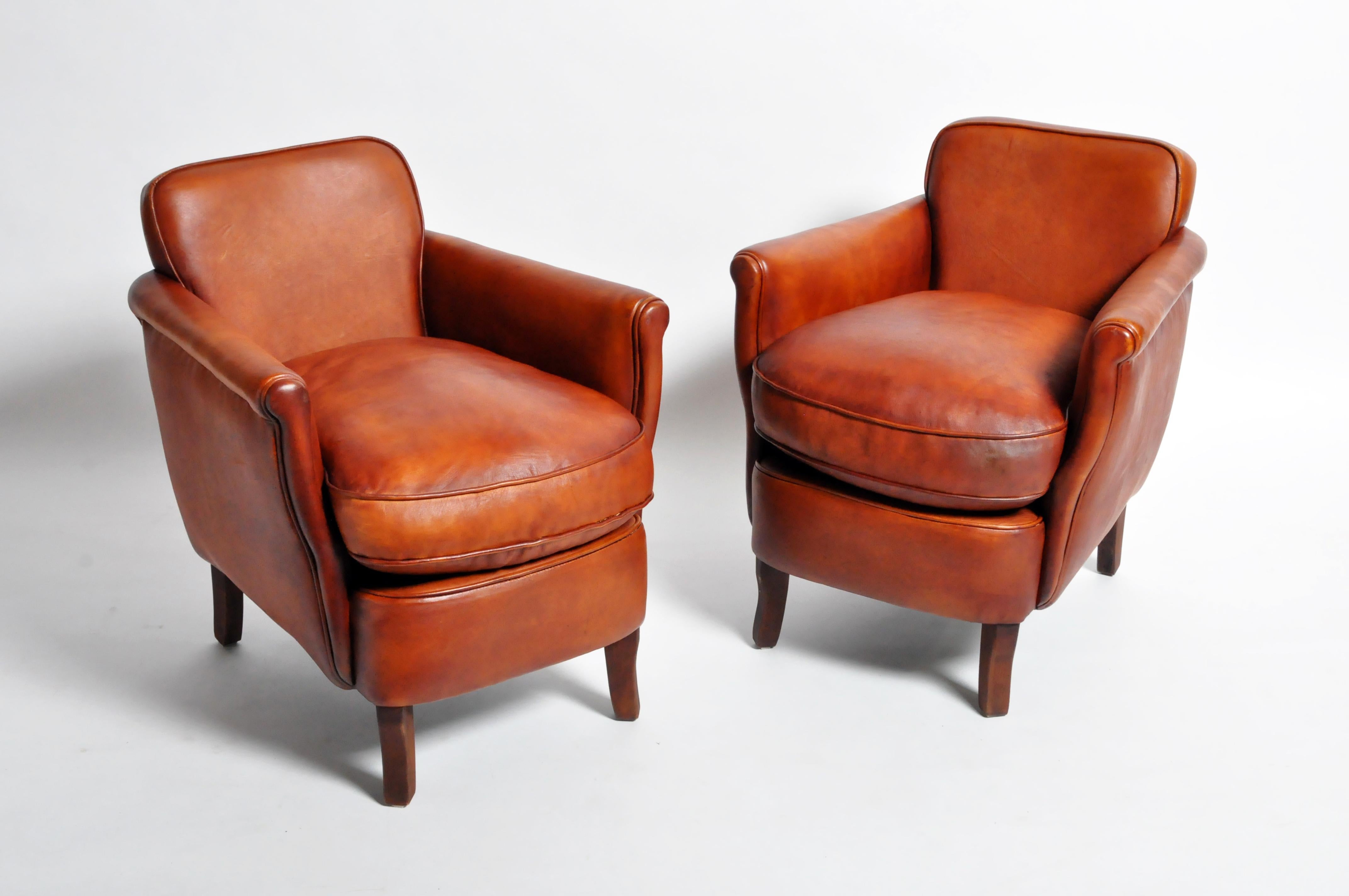This newly made pair of armchairs are from France and made from leather and wood. The chairs feature black piping and are comfortable and sturdy, ready for daily use.