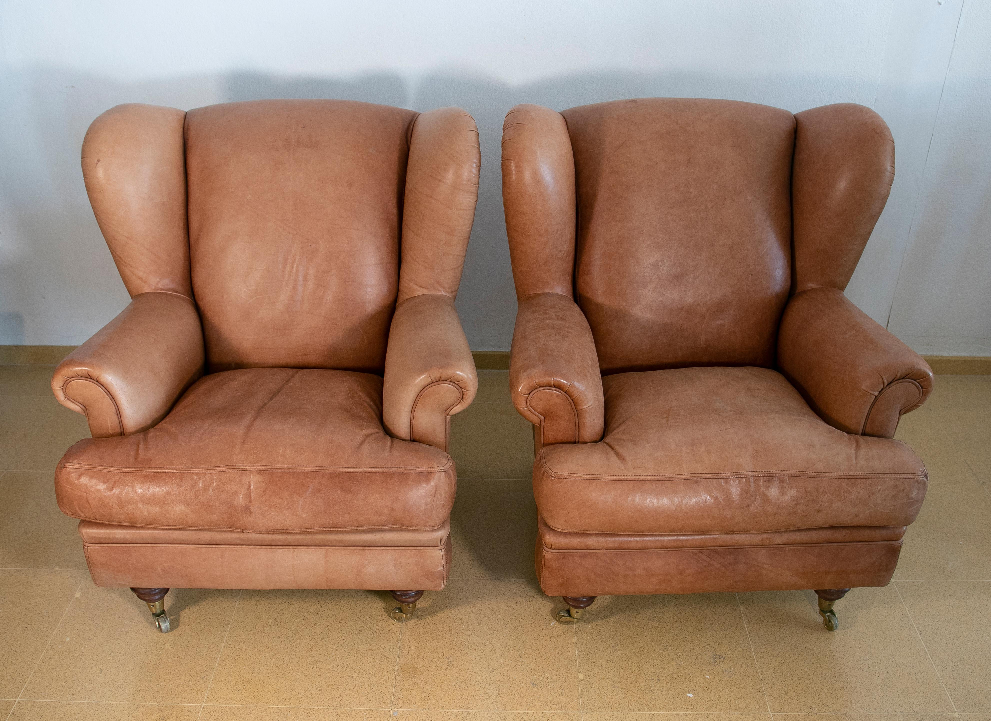 20th Century Pair of Brown Leather Armchairs with Wooden Legs and Brass Wheels For Sale