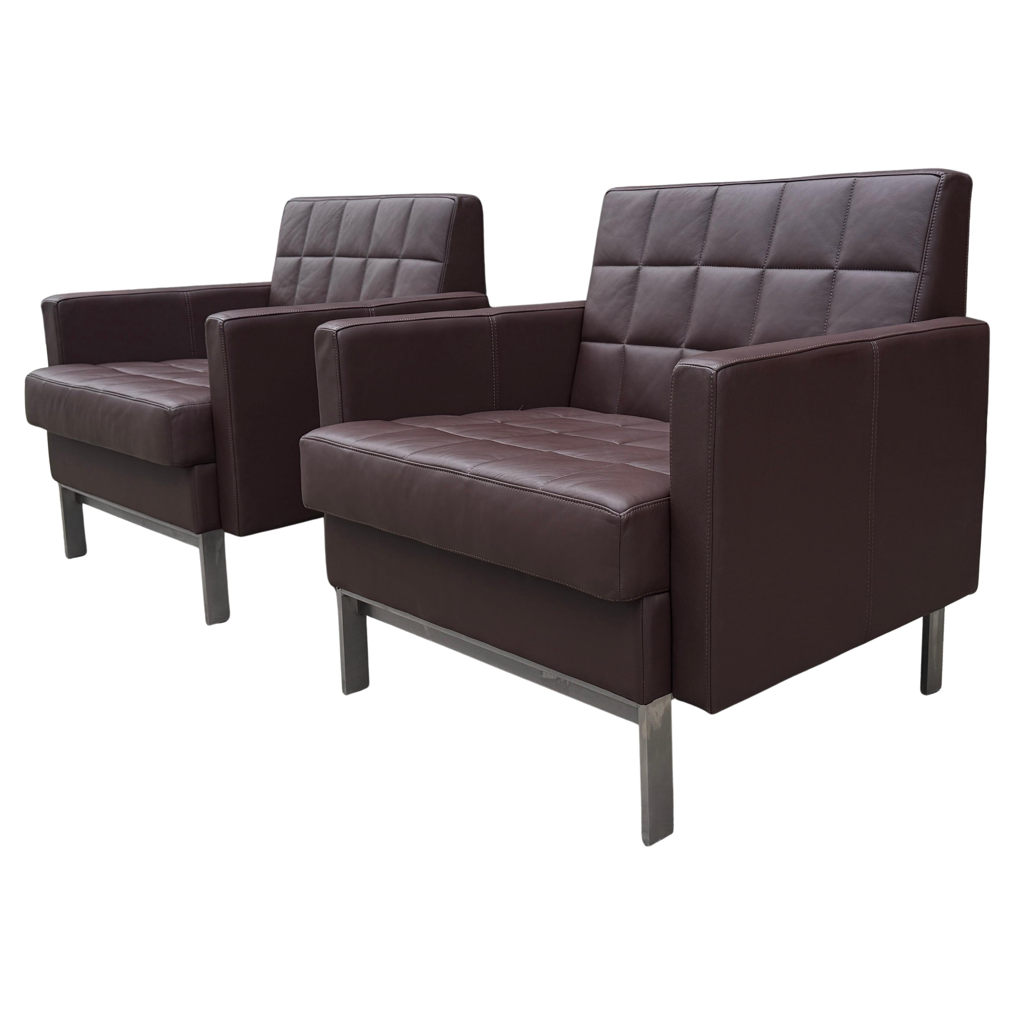 This pair of Steelcase Millbrae lounge chairs offers firm comfort and exceptional support with a sleek, modern design. The quilted leather cushions, inspired by classic tufted upholstery, rest on a low-profile horizontal steel base that nods to