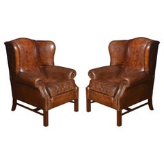 Antique Pair of brown leather upholstered wingback armchairs