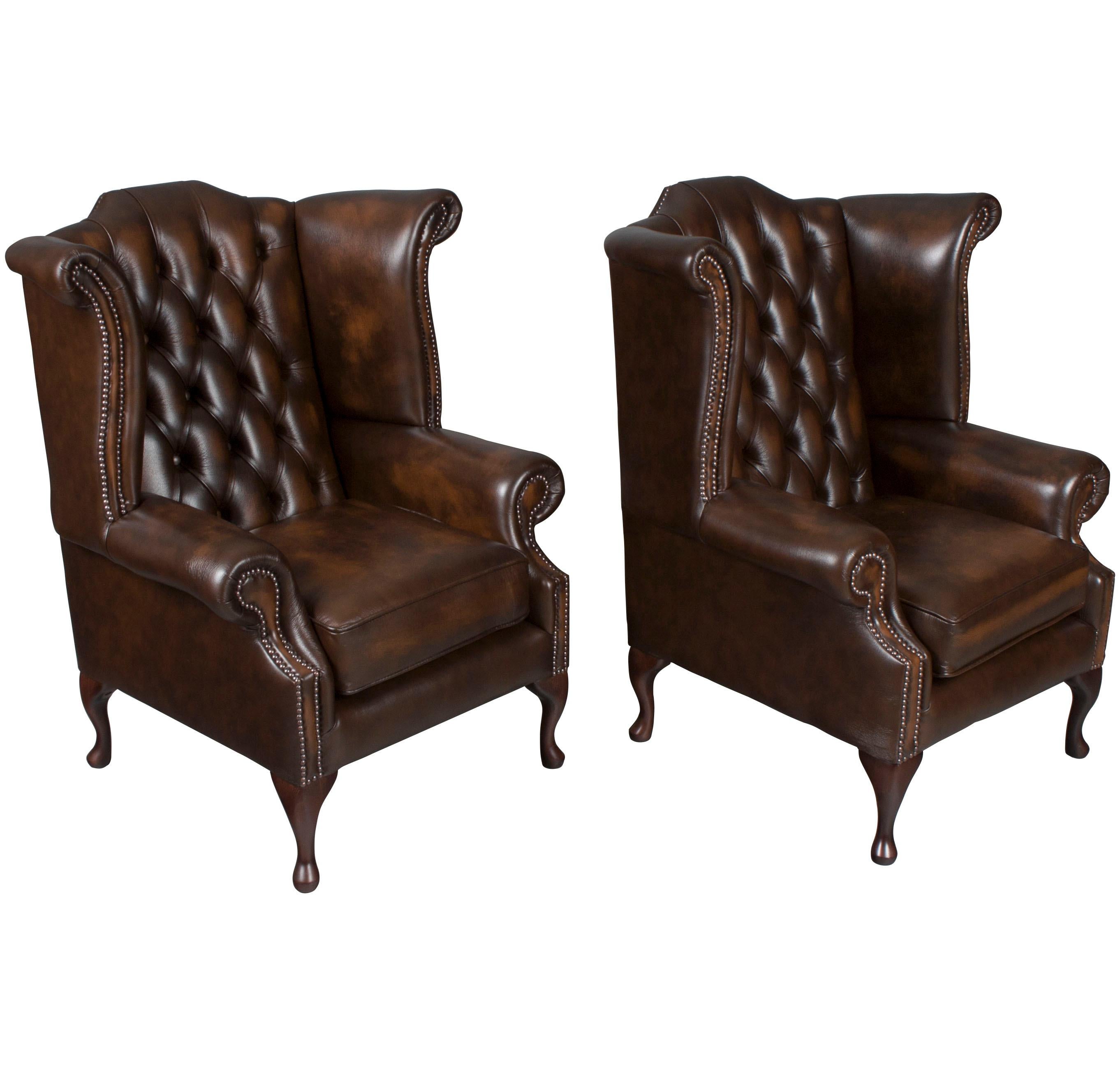This is a brand new set of hand made tufted leather wing back arm chairs from England. 

The brown tufted leather used is a genuine, semi-aniline dyed leather. The maker expertly antiques it to provide an aged look with lighter tones on the raised