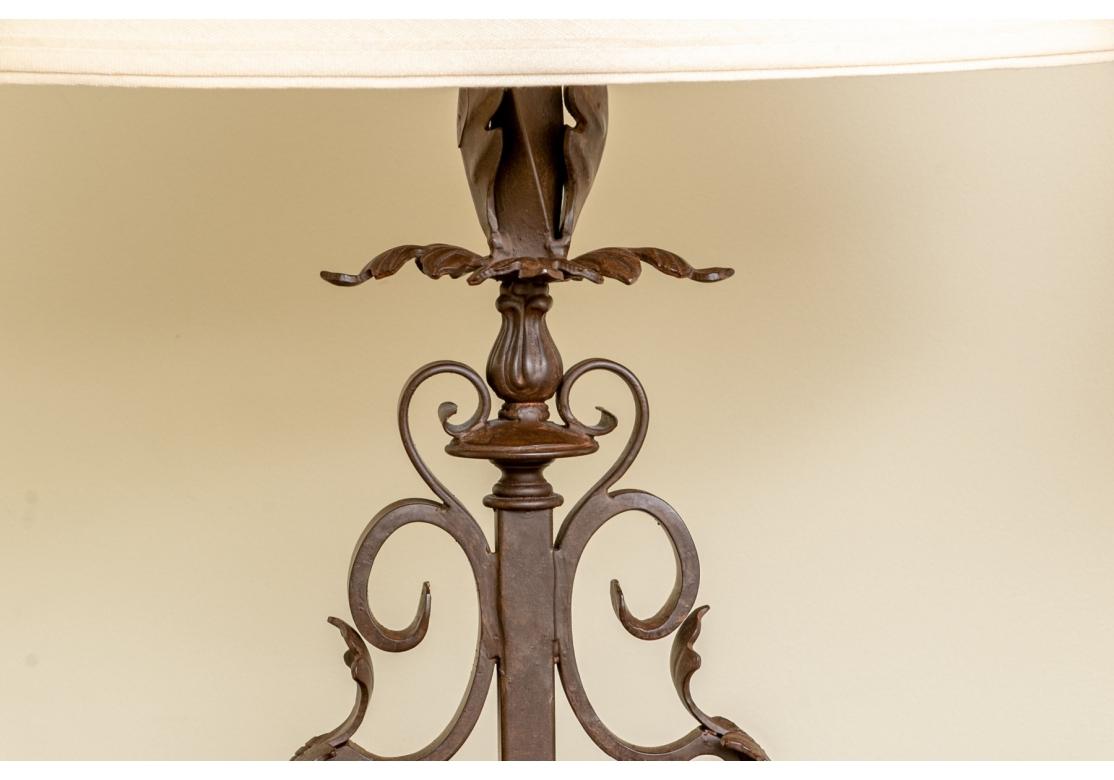 Pair of brown patinated wrought iron table lamp with acanthus leaf decorated scrolls, covered in linen hard back shades. The lamps have good weight and deep brown patinated finish and the shades have a light linen presentation. 

Dimensions: 25