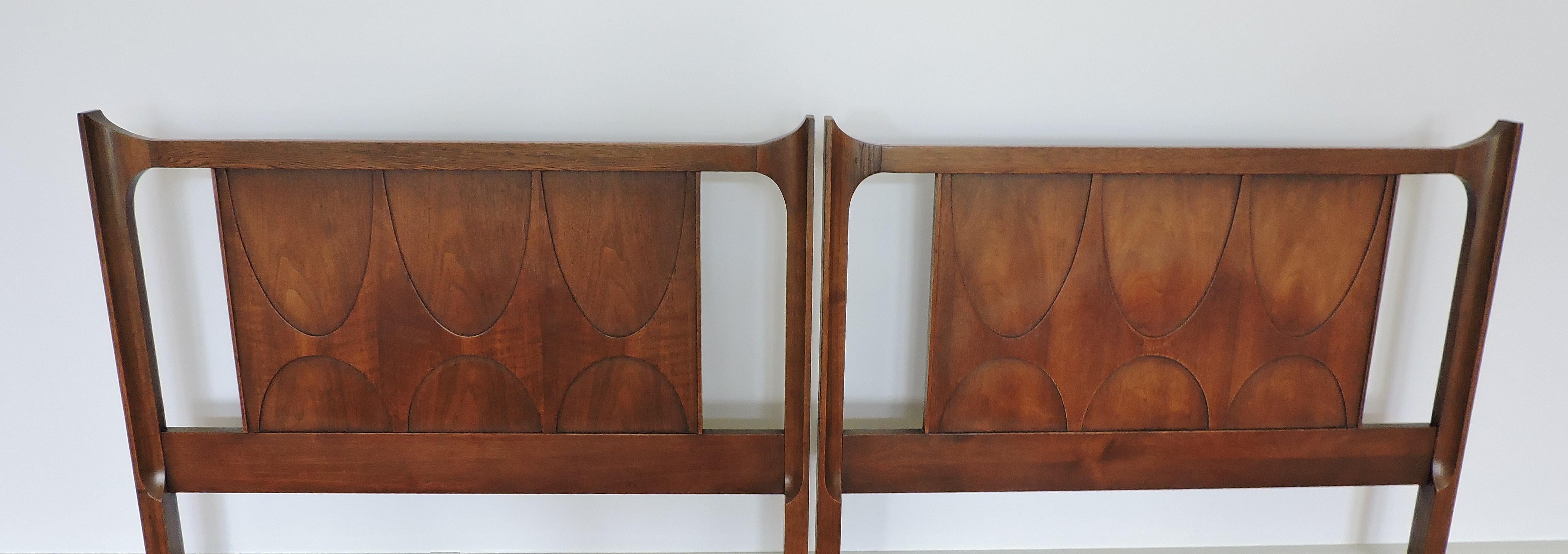 Distinctive pair of walnut twin beds which were part of Broyhill's Brasilia line that was inspired by Oscar Niemeyers Mid-Century Modern Brazilian architecture. These beds have headboards with arched details. Unmarked, but were part of a set that