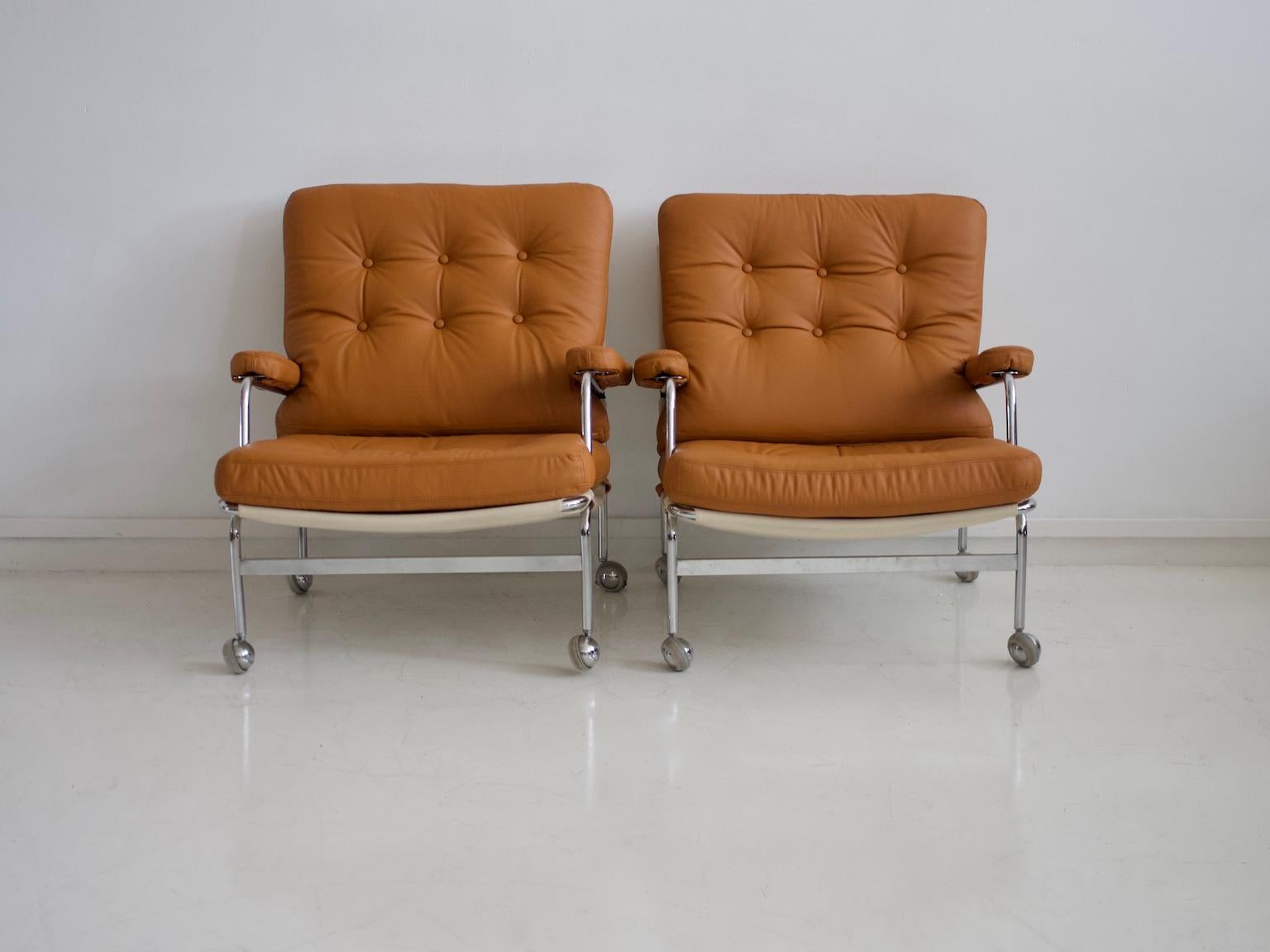 Pair of armchairs, model 'Karin', designed by Bruno Mathsson 1969 and produced by Dux. Frame in chrome-plated metal, legs fitted with castors. Cushions and armrests newly upholstered with brown leather, reusing the original fabric by the maker
