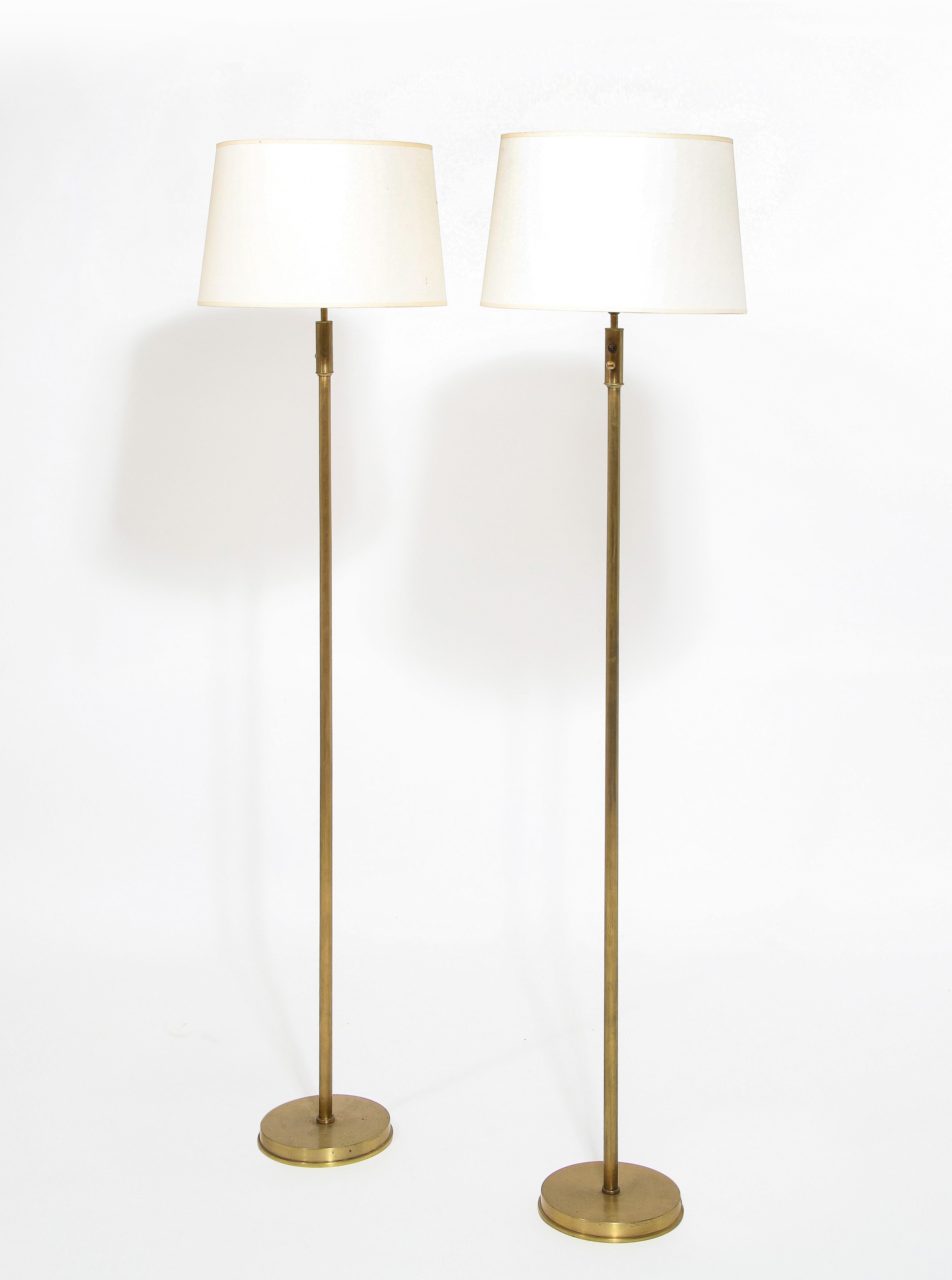 Elegant pair of brushed brass floor lamps on circular bases. Shades are for photographic purposes.