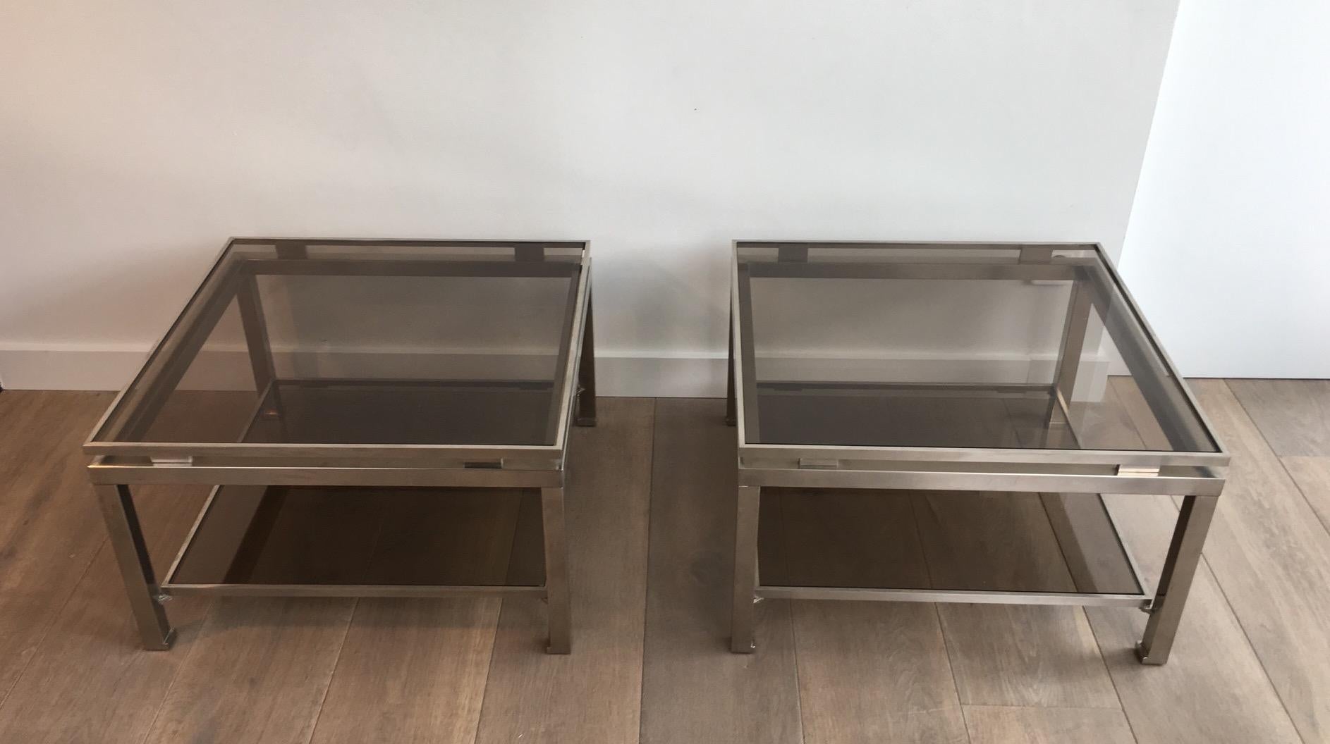 This rare and beautiful pair of side tables is made of brushed steel with smoked glass shelves. The model is rare, really nice and the quality very good. This is a French work by famous designer Guy Lefèvre for Maison Jansen. Circa 1970.