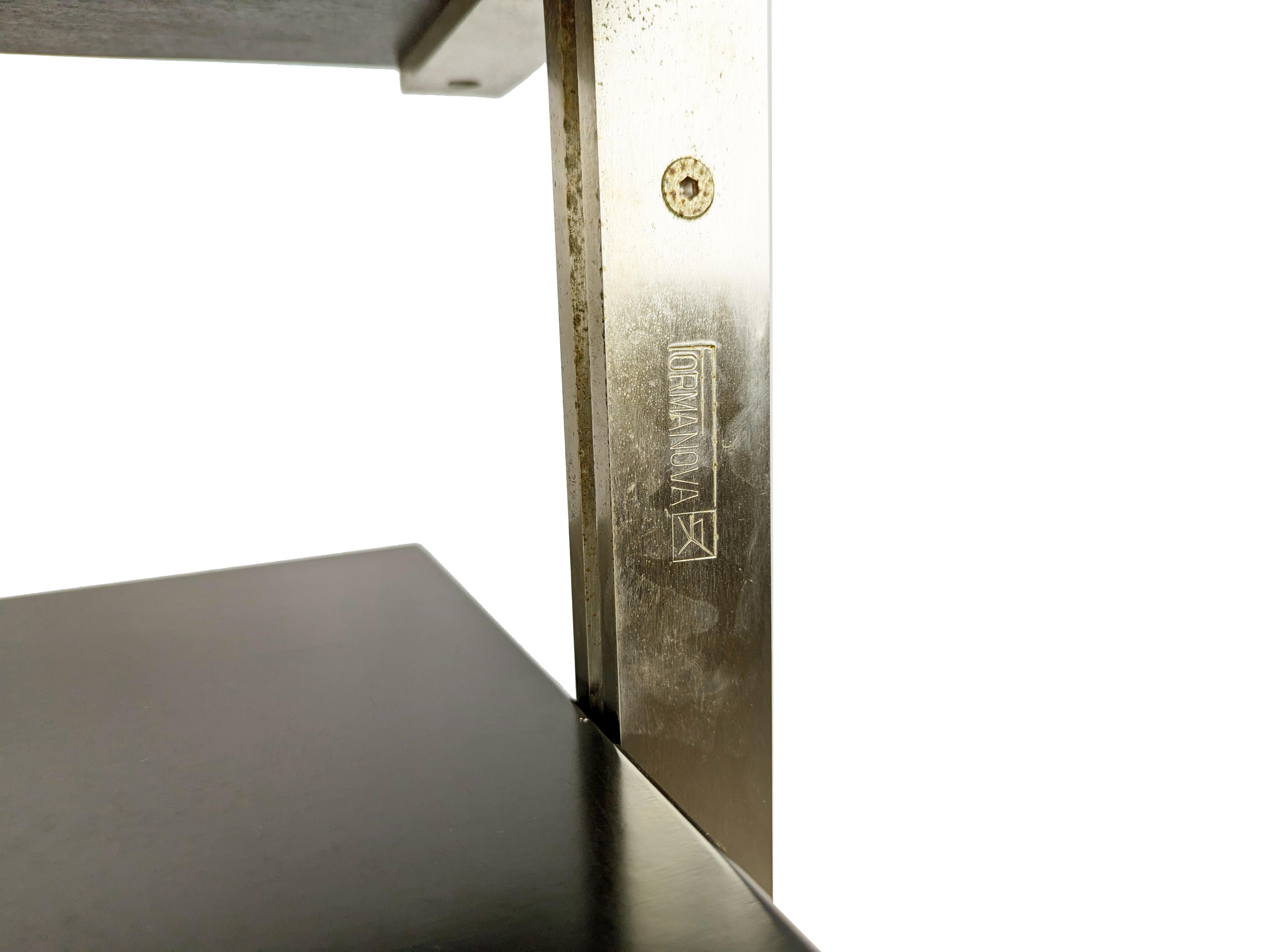 Structure solide en métal brossé avec roues pivotantes et 2 étagères en bois teinté brun foncé. Les étagères en bois restent en assez bon état, mais l'une d'entre elles présente des rayures visibles sur un petit côté, comme le montrent les photos.