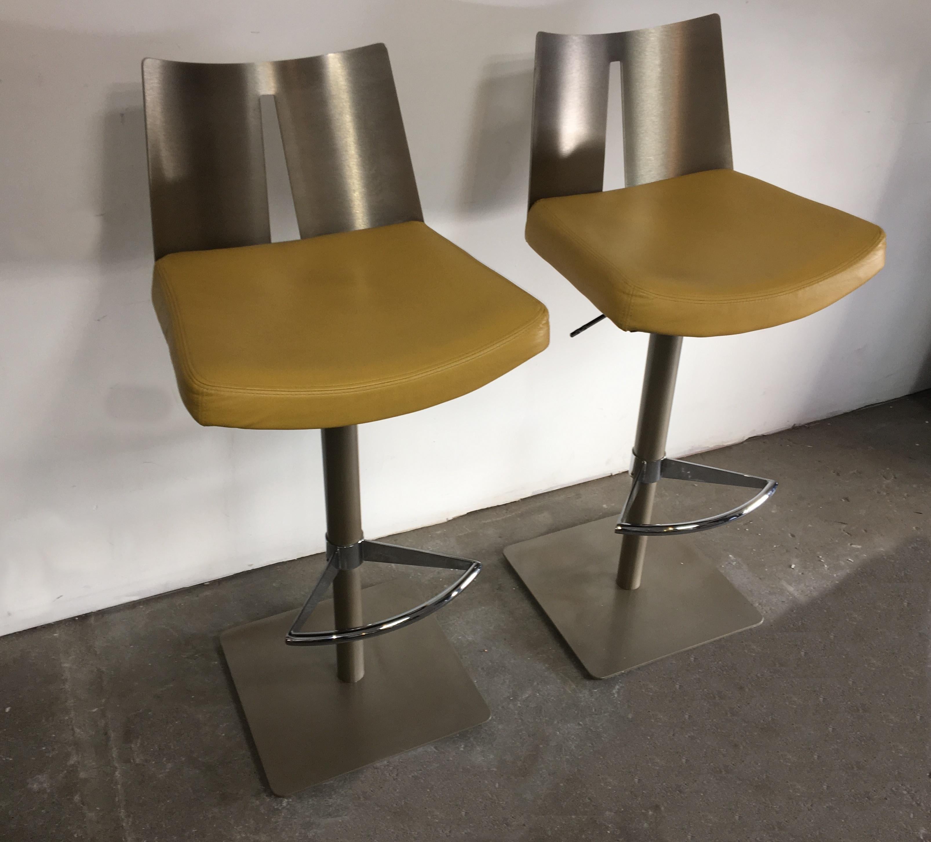 Pair of height-adjustable swivel bar stools.
As you can see on the picture, to adjust the height of the stool, the bottom part under the footrest, becomes shorter. 

Grey powder-coated steel base and column.
Shiny polished steel footrest and