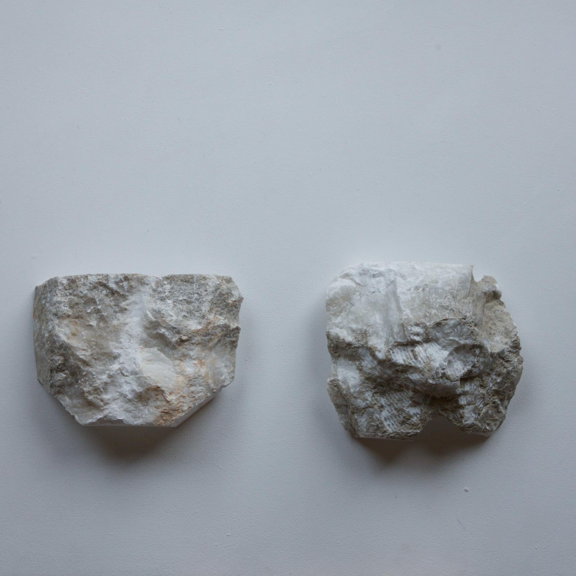 A large pair of brutalist stone wall sconces in marble. The raw edge has been celebrated here and the internal sconce has been carved out and a wall fixing inserted. The sconces are to be hung over existing light fittings. They glow when
