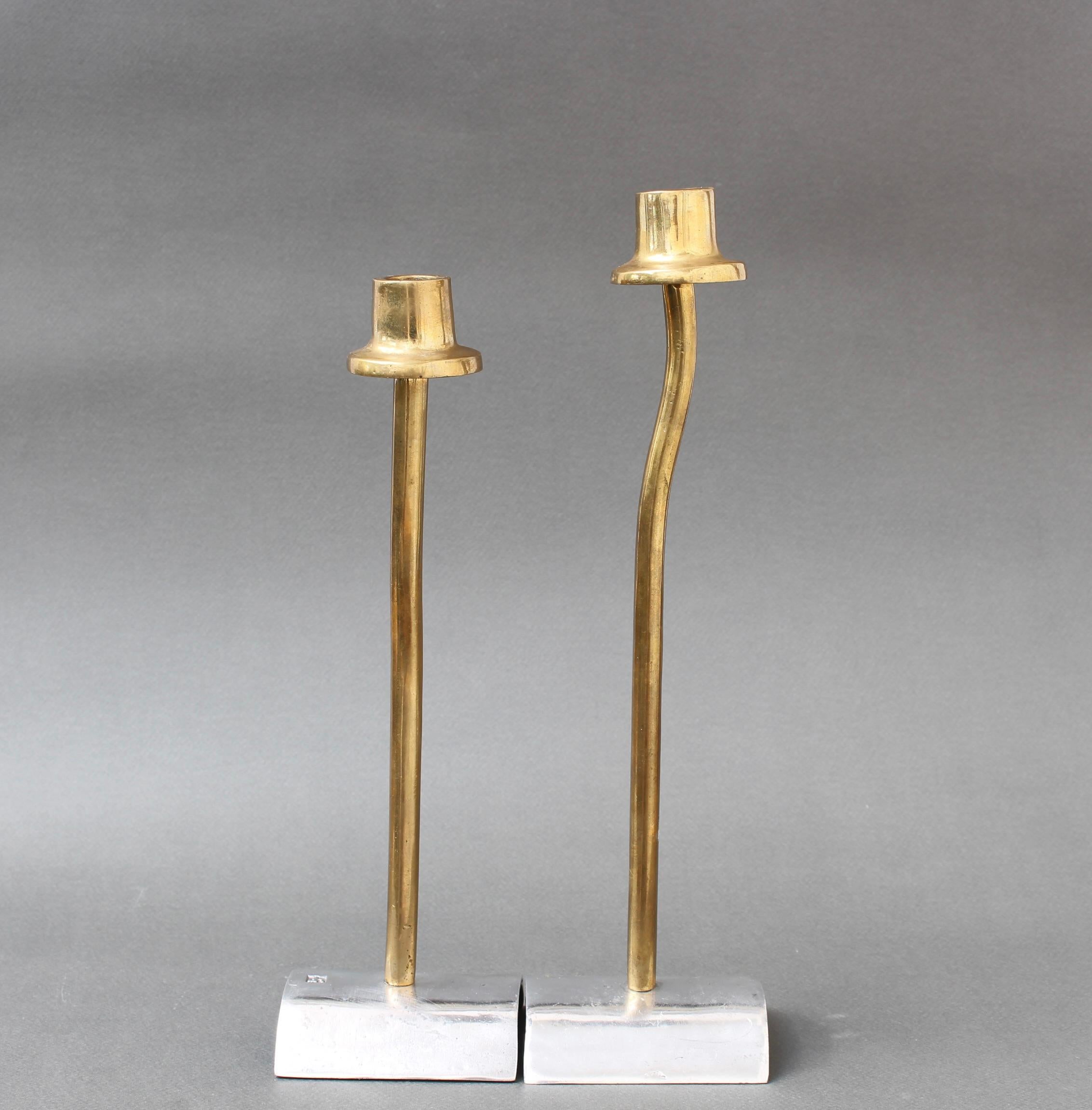 Pair of brutalist aluminium and brass candlesticks by David Marshall (c. 1980s). These brutalist style candlesticks are both weighty and tactile with the maker's mark impressed on the surface near the base of the shorter one. The bases are raised