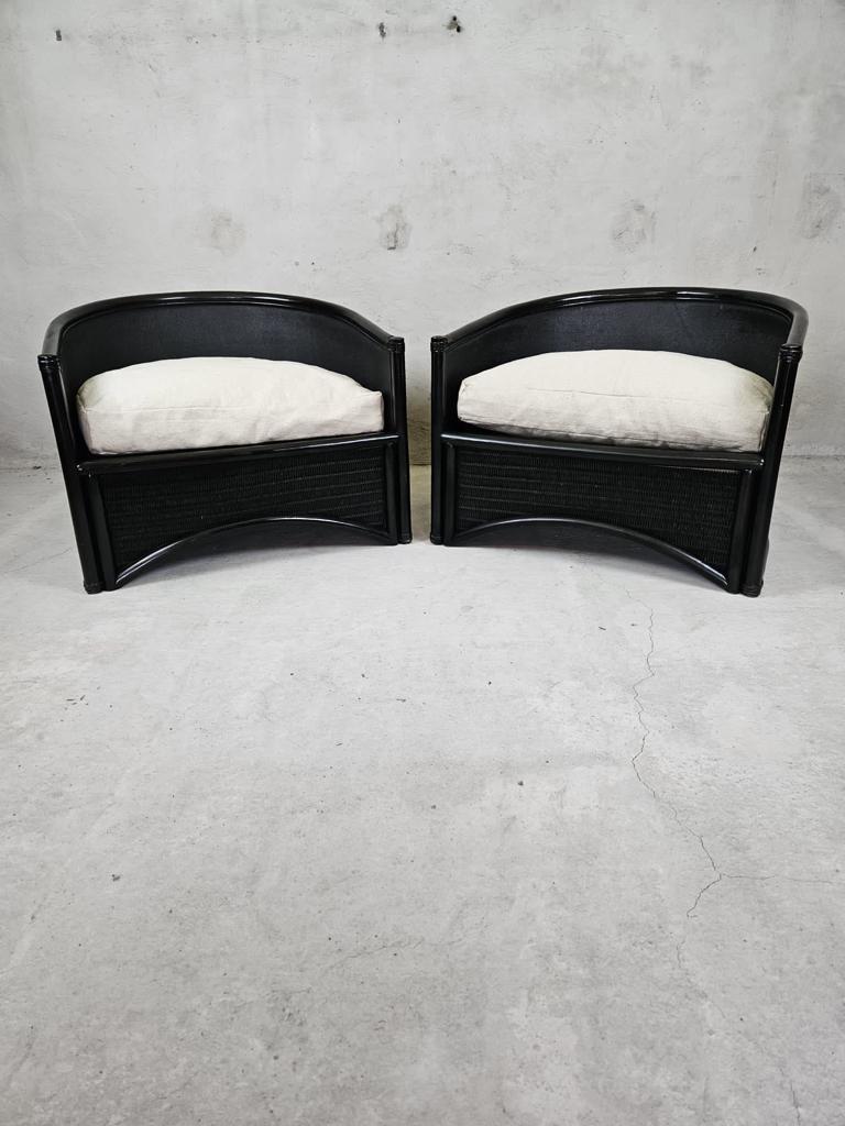 A stunning pair of brutalist black rattan lounge chairs with newly upholstered cushions.