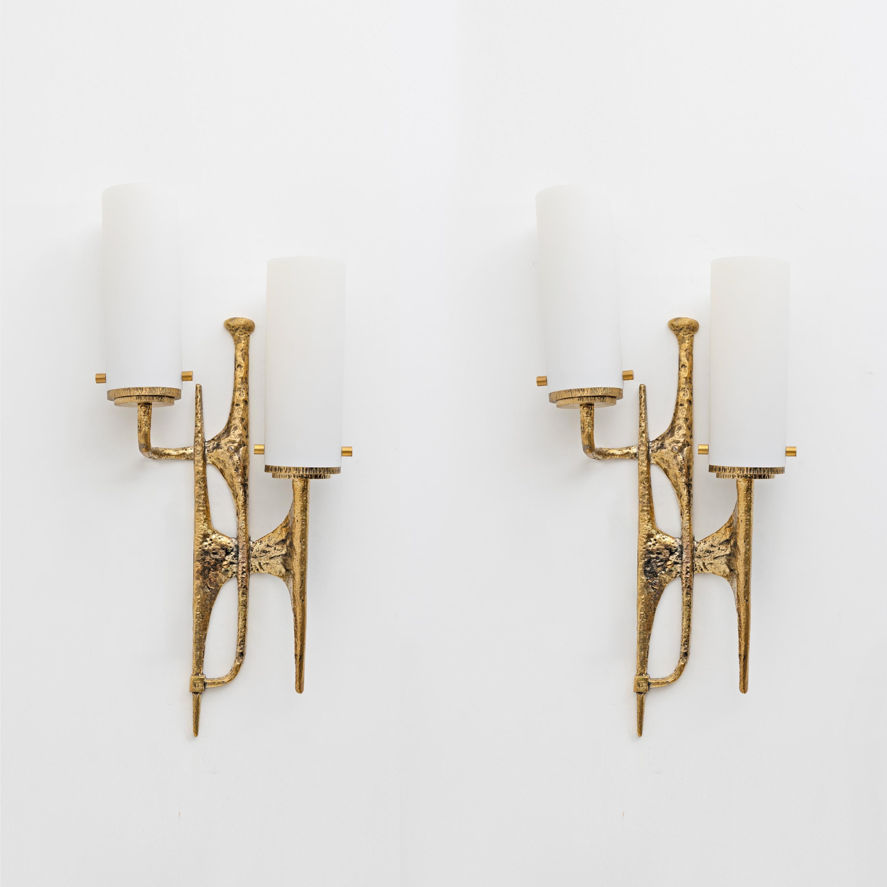 Pair of Brutalist cast bronze wall lamps, made in the Maison Arlus style, in the manner of Felix Agostini.
This pair of wall lamps is in gilded bronze. It is inspired by the bark of trees and their branches thanks to a very particular hammering