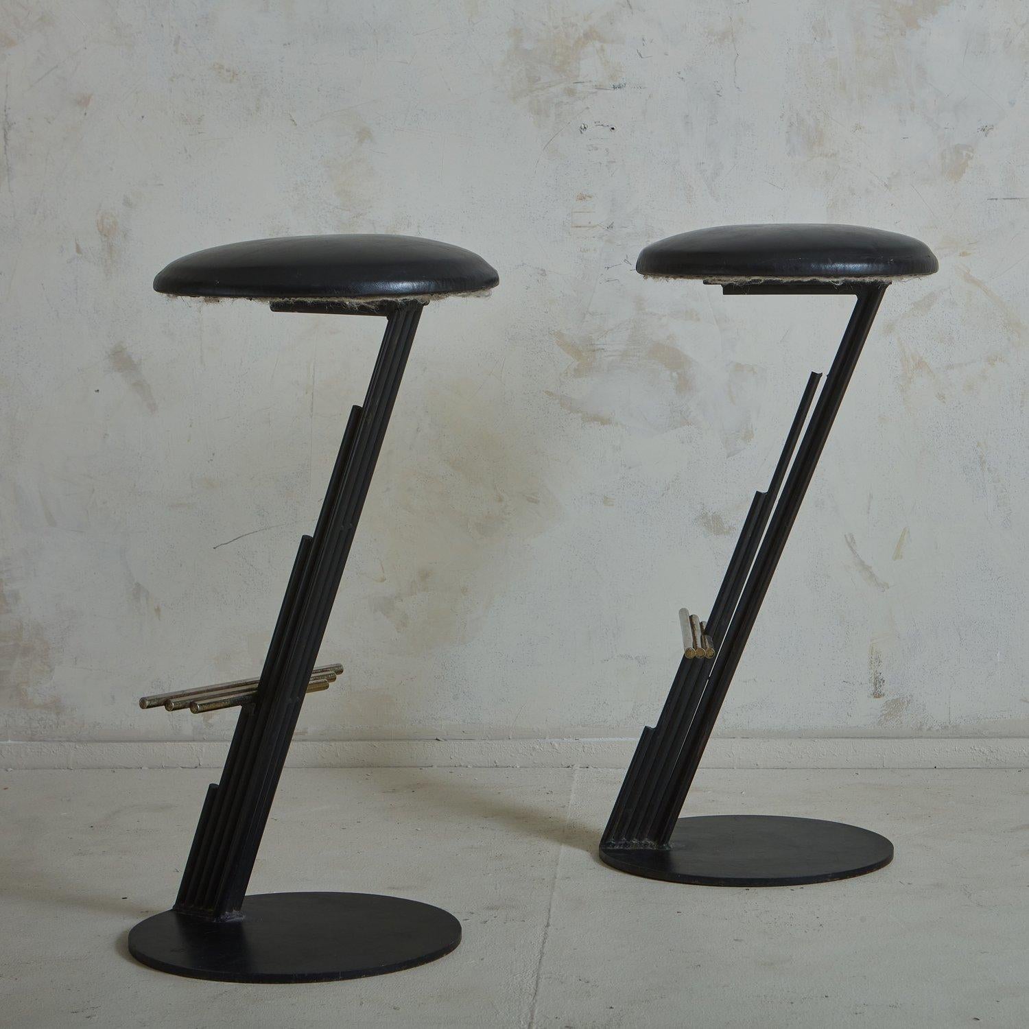 A pair of sculptural 1980s Brutalist stools by Curtis Jere (1910-2008) featuring a cantilever black enameled metal Z frame with layered rod details. These stools have circular metal bases and upholstered seats in original black leather. They have