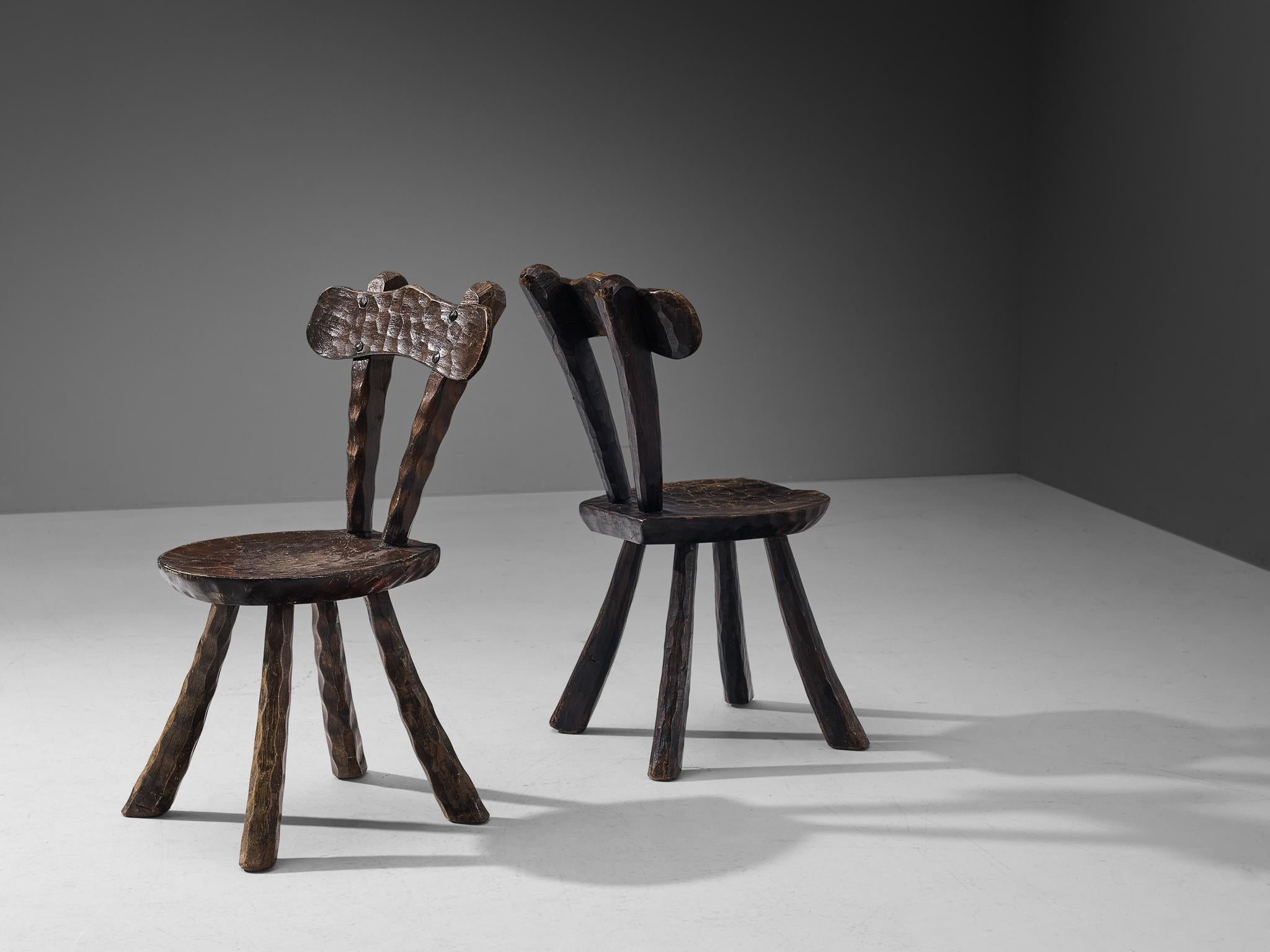 Side chairs, dark stained elm, France, 1960s. 

Pair of Brutalist chairs in the manner of Alexandre Noll. These French chairs show the characteristic traits of his furniture designs; the frame exhibits prominent carving details creating a