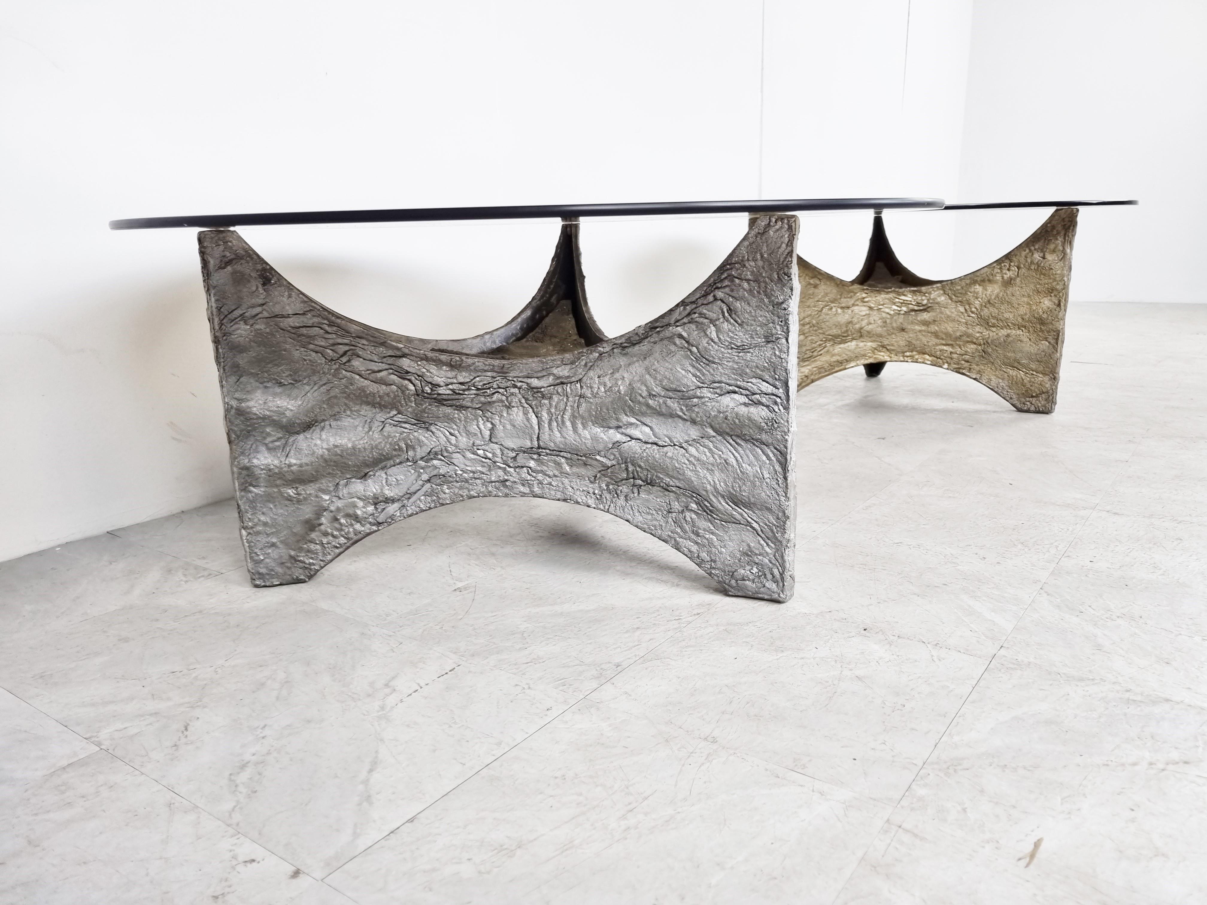 Spectacular coffee tables with a cast aluminum base and a smoked glass top. 

Beautiful statement piece that mixes well with most interiors.

Designer/artist unknown, very much in the style op Willy Ceyssens or Paul Evans

Good condition,