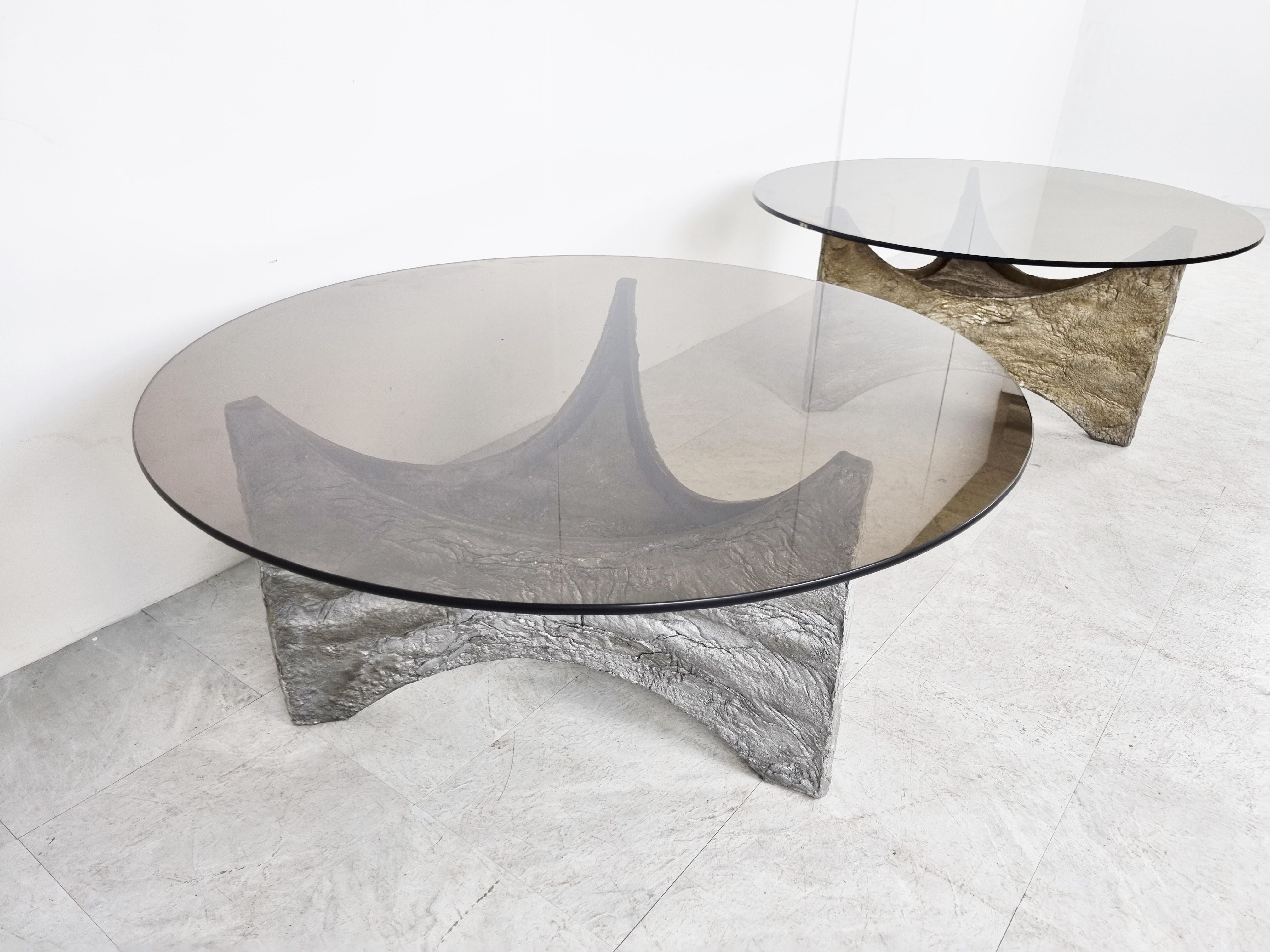 Spectacular coffee tables with a cast aluminum base and a smoked glass top. 

Beautiful statement piece that mixes well with most interiors.

Designer/artist unknown, very much in the style op Willy Ceyssens or Paul Evans

Good condition, slight