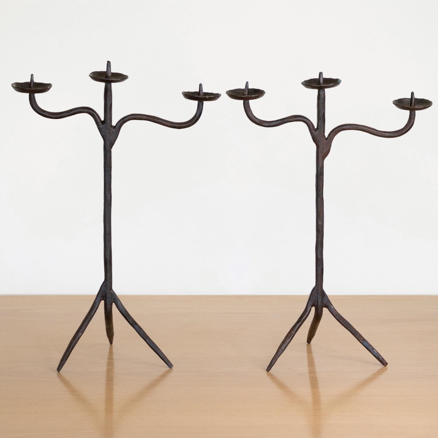 Fantastic pair of Brutalist candlesticks handcrafted in wrought iron and attributed to Atelier de Marolles, France, 1950s. Simple yet whimsical form each with three candle holders and tripod base. In good condition with nice age and patina.