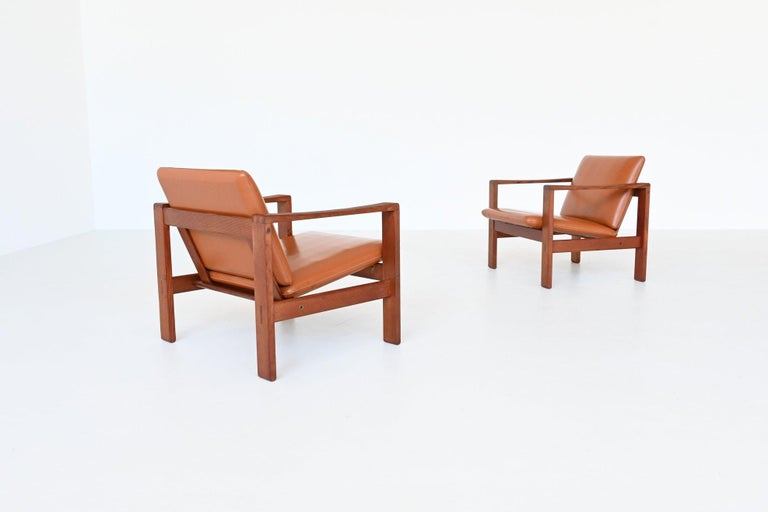 Fantastically shaped pair of Dutch lounge chairs by unknown designer or manufacture, The Netherlands 1960. These well-crafted chairs feature a solid frame of pine wood with orange brown faux leather upholstery. Some very nice details are the tapered