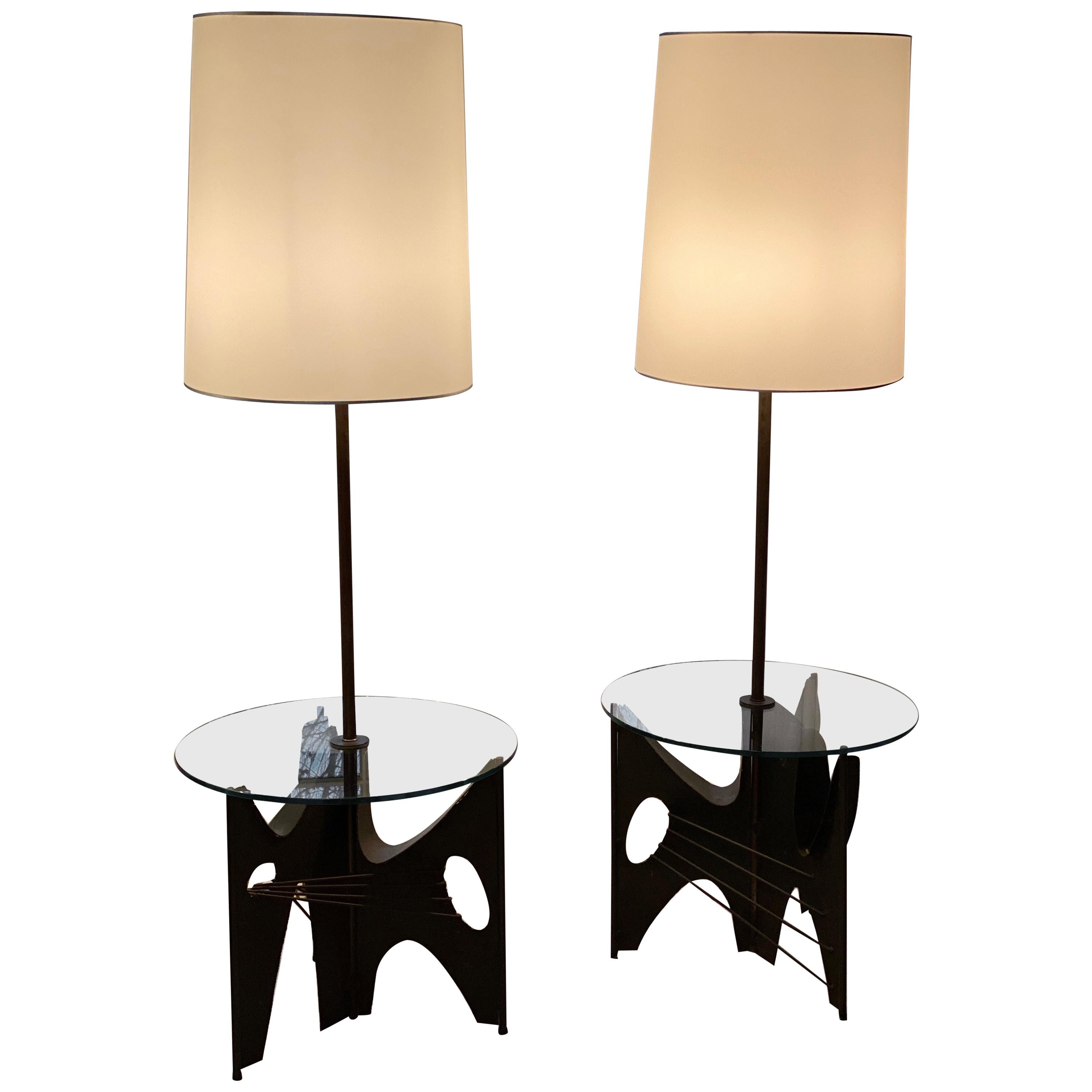 Pair of Brutalist metal floor lamps with table by Harry Balmer for Laurel.
Black metal base and stem with round glass table tops. Shades were custom made for lamps, not original shades.
Measures: 18” x 22” shade
Glass top 22” round
Approx 60”