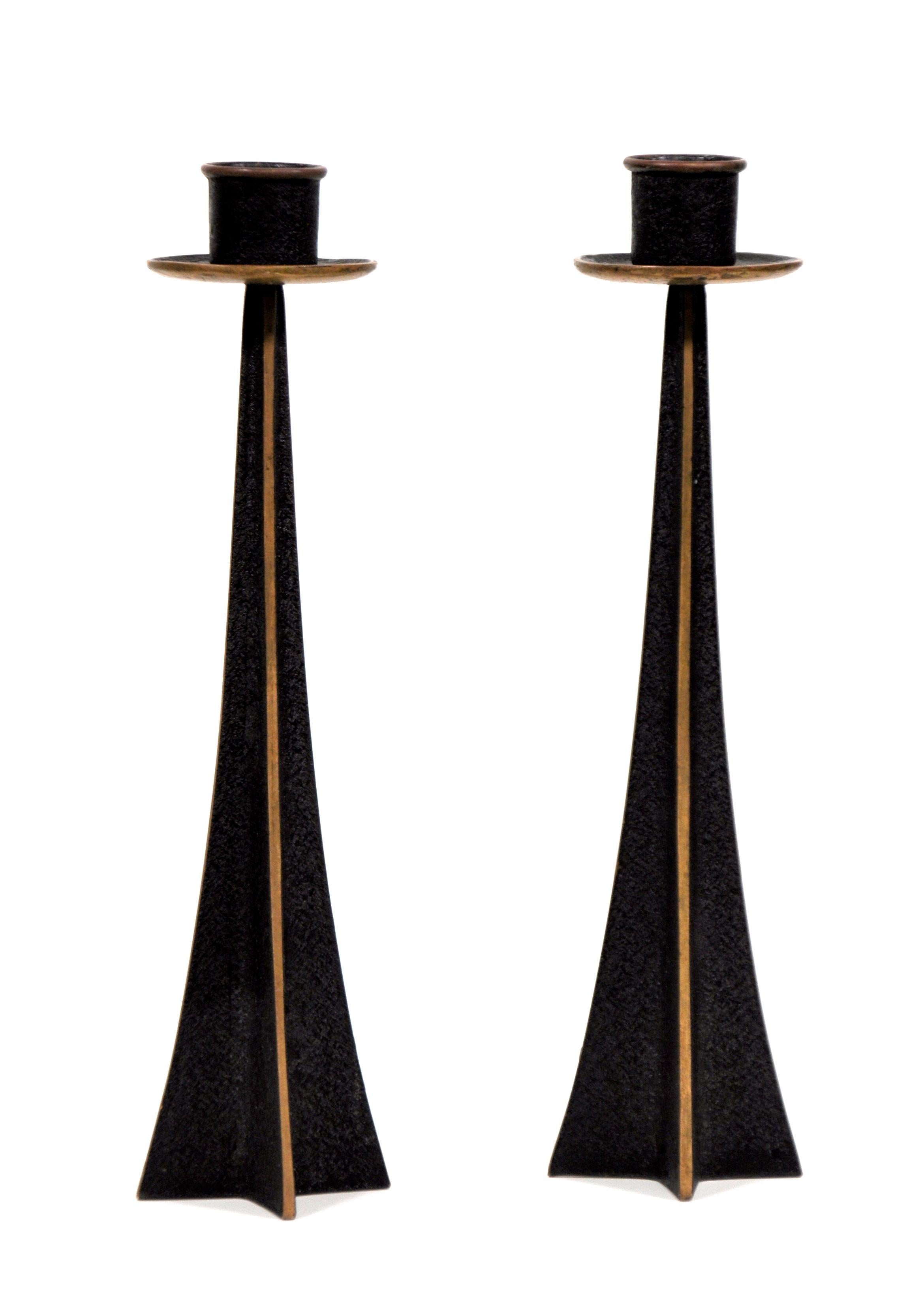 Pair of vintage midcentury Danish modern bronze candleholders of tapered stylized star, X or cross shaped body topped by a round bobeche. The metal has a black, textured finish contrasting with the gold tone of the polished borders. Work well with