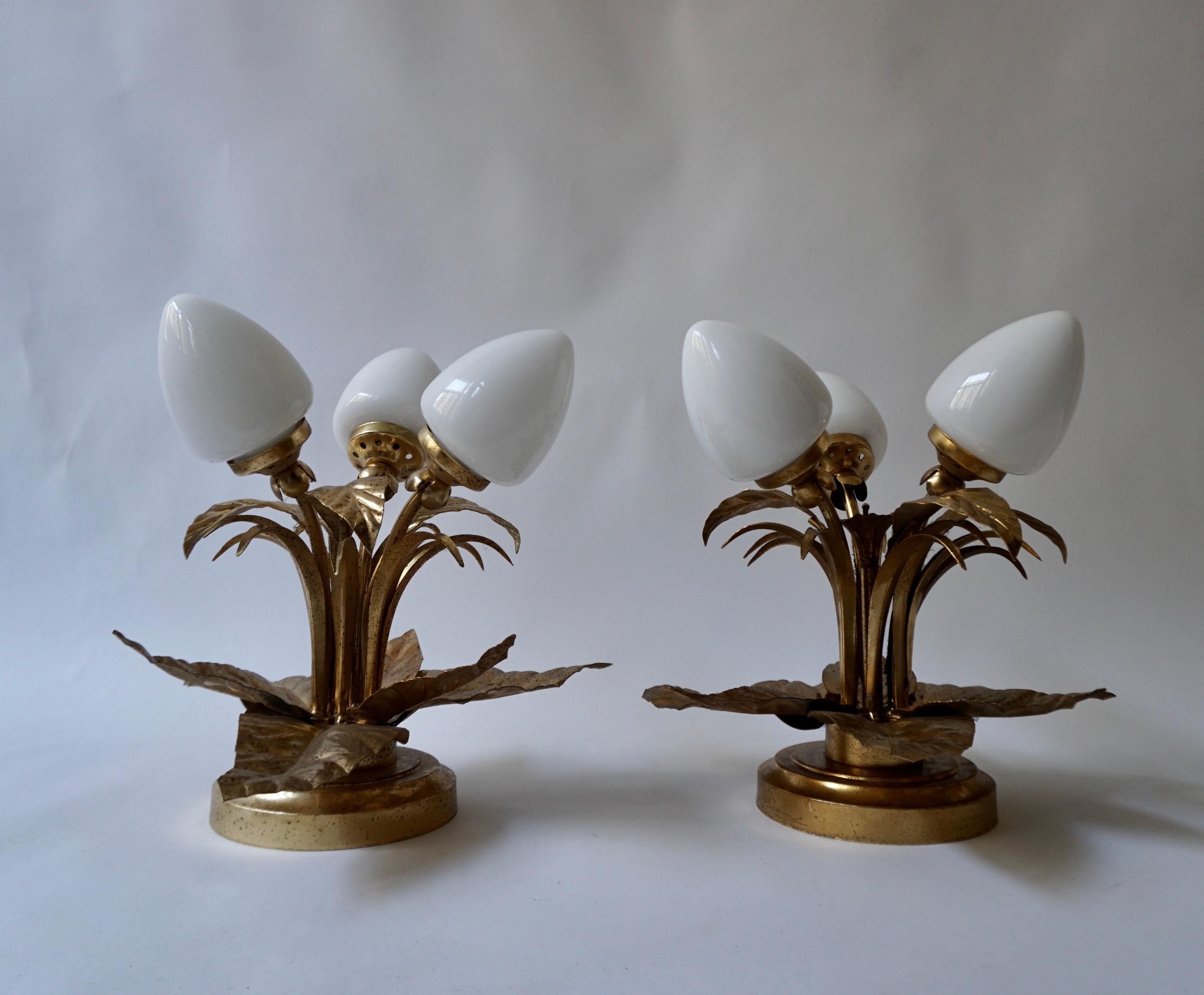 Two Flower-shaped flush mount, gilded iron, gold leaf, Italy, 1950s. These striking lighting fixtures are made of hand-carved iron and consist of two layers of gilded leaves in two shades with three white glass shades in the middle. They have a