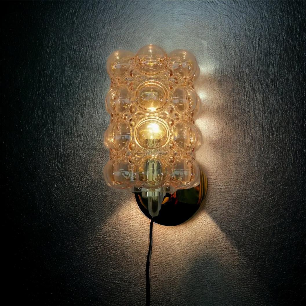 A beautiful and rare midcentury amber glass pair of sconces designed by Helena Tynell for Glashuette Limburg (Germany, 1960s). The amber or champagne colored hand blown bubble glass shade casts a wonderful light (see image). A Mid-Century Modern