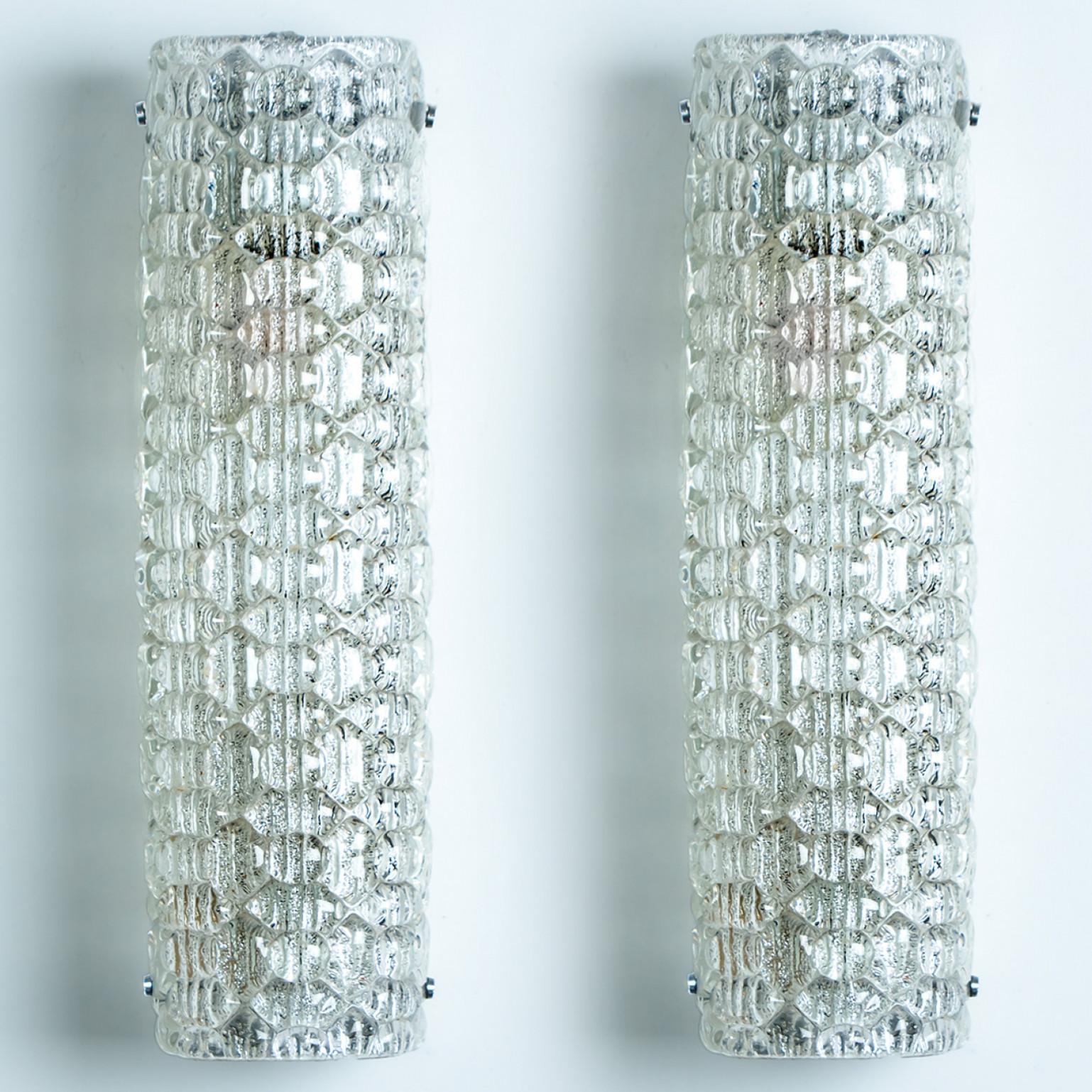 Clean lines to complement all decors. Wonderful high-end wall light fixtures with brass detail and thick bubbled blown glass. Manufactured in the 1960s.
The glass of the light fixtures are made of ice glass giving the piece a heavy ice appearance