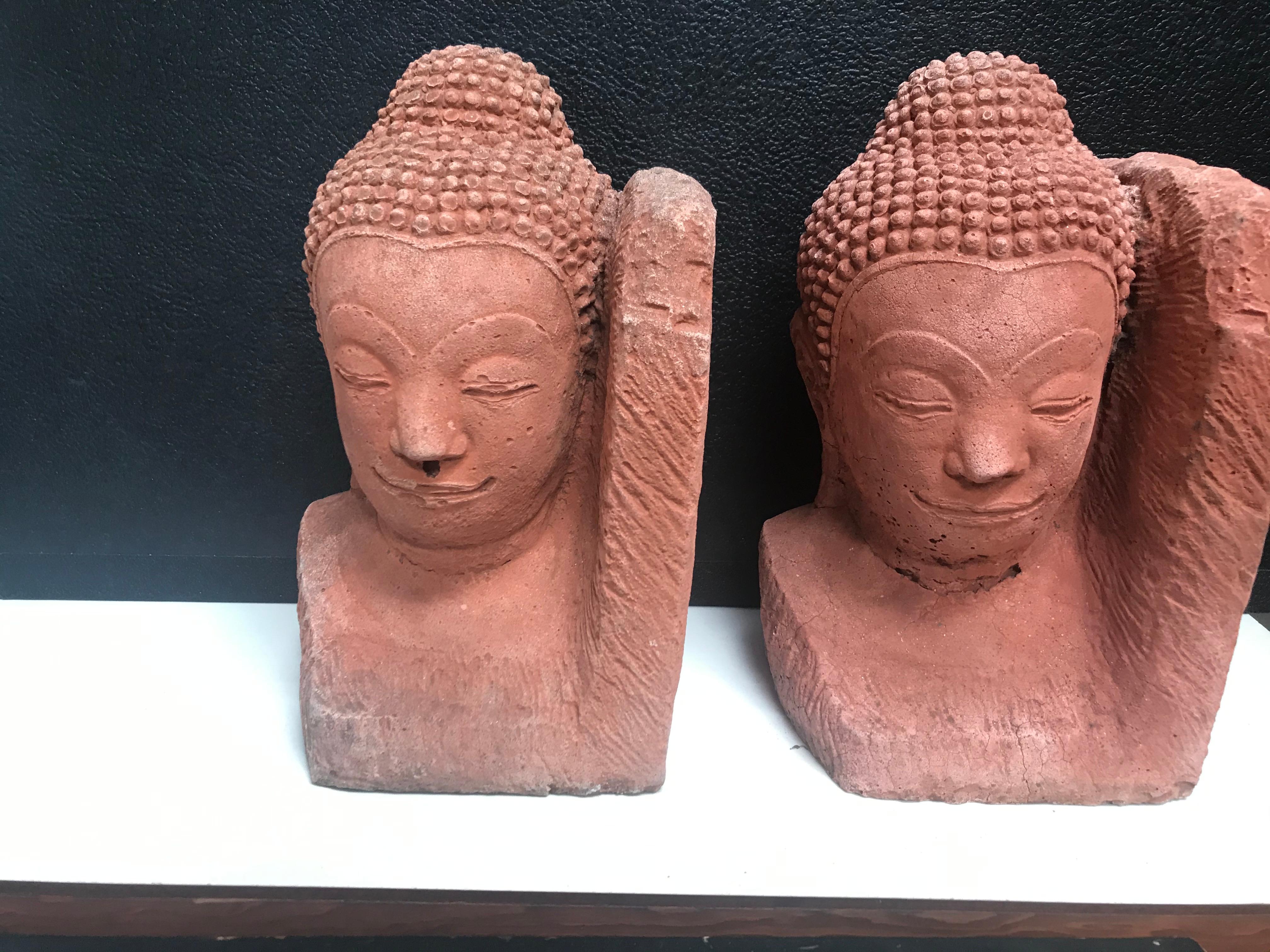 A pair of Buddha heads bookends made of terracotta.