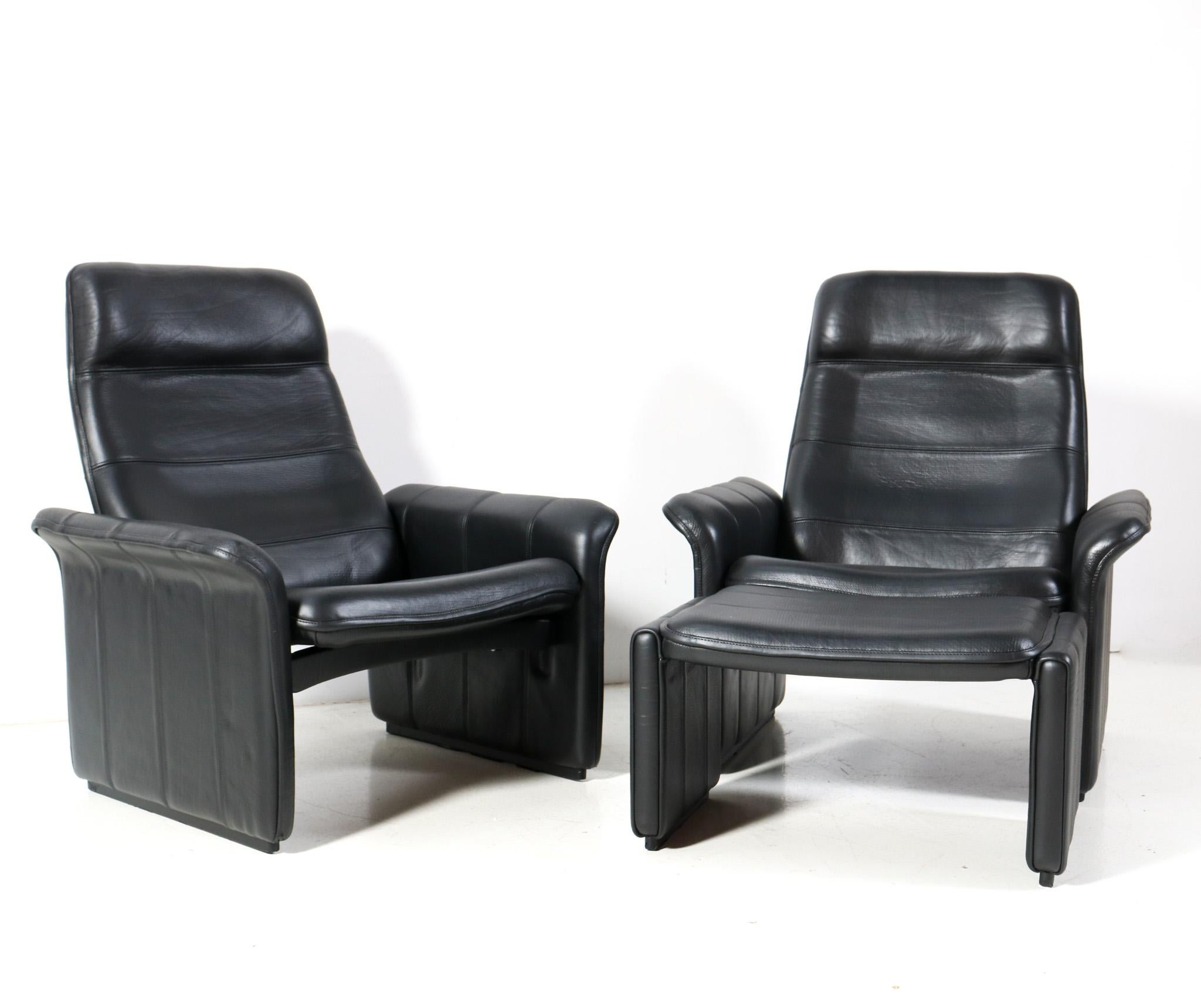 Stunning and elegant pair of Mid-Century Modern DS-50 recliner lounge chairs with one ottoman or hocker.
Design by the famous company De Sede Switzerland.
Striking Swiss design from the 1970s.
Original solid wooden frames with hand stitched black
