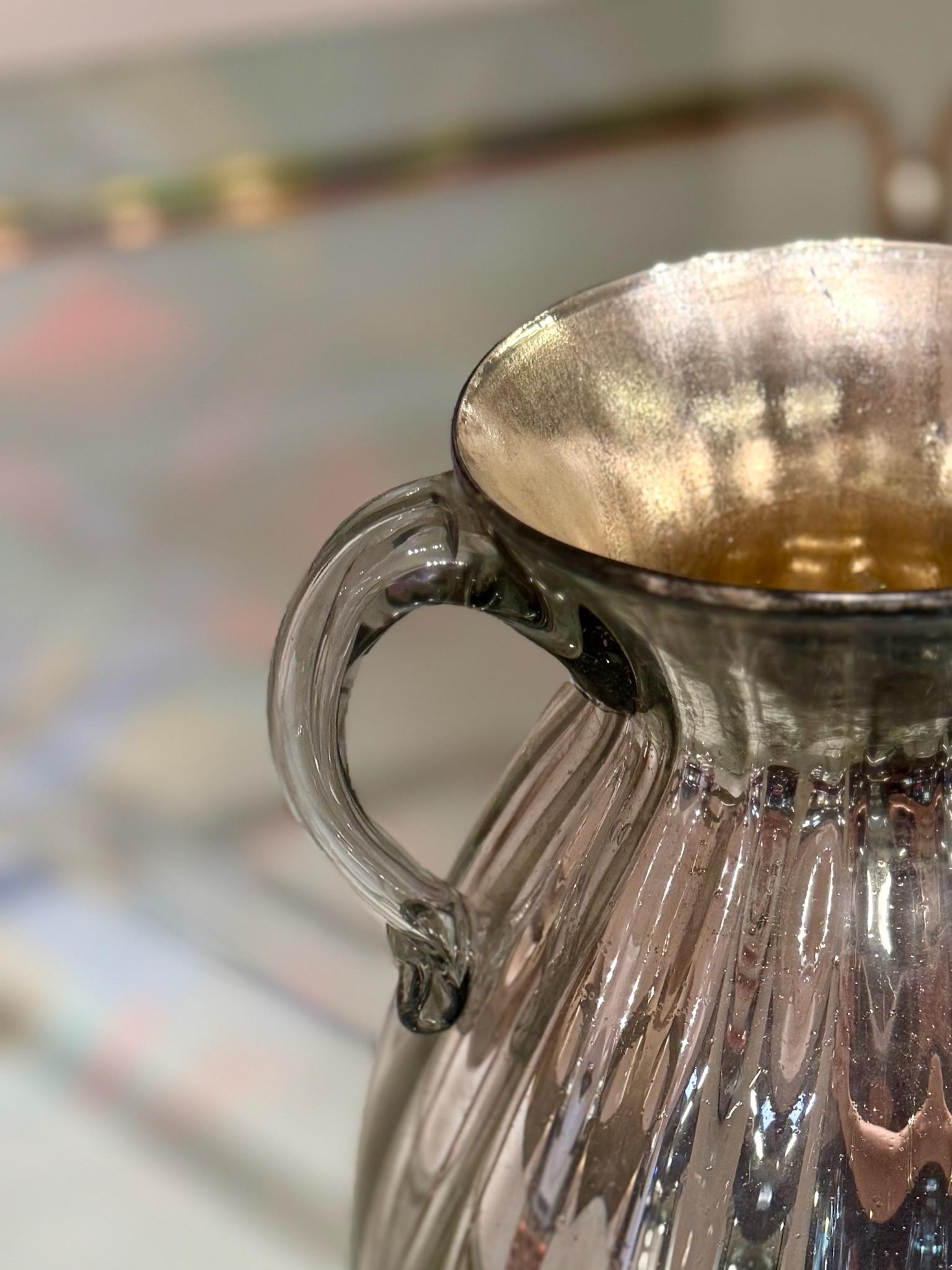Cette paire de vases en verre bulbeux se distingue par sa finition argentée et miroitante et ses élégantes lignes verticales nervurées. Chaque vase est doté d'une double poignée gracieusement incurvée, ajoutant à la fois symétrie et raffinement à